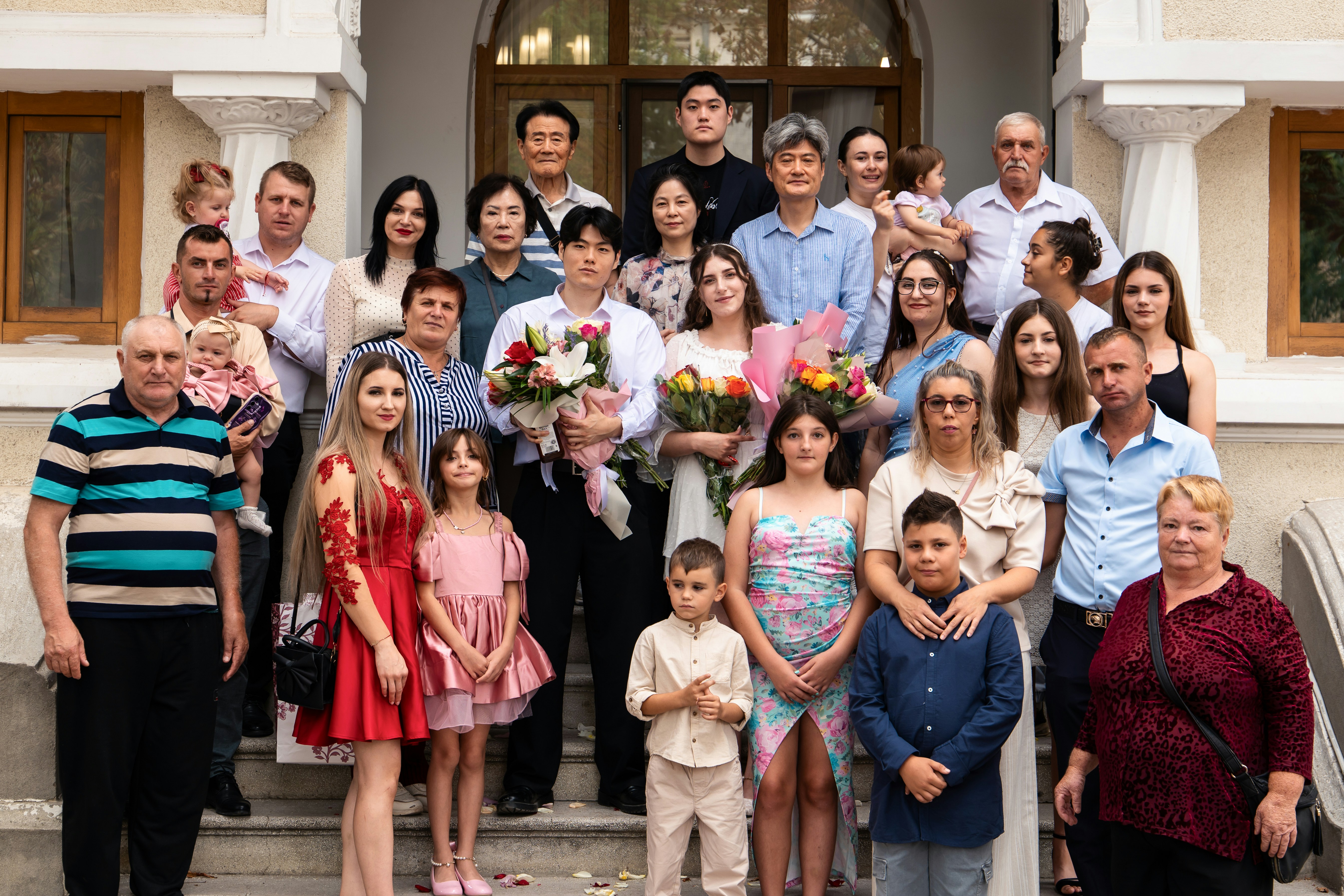 A large family posing for a group portrait on stone steps outside a building