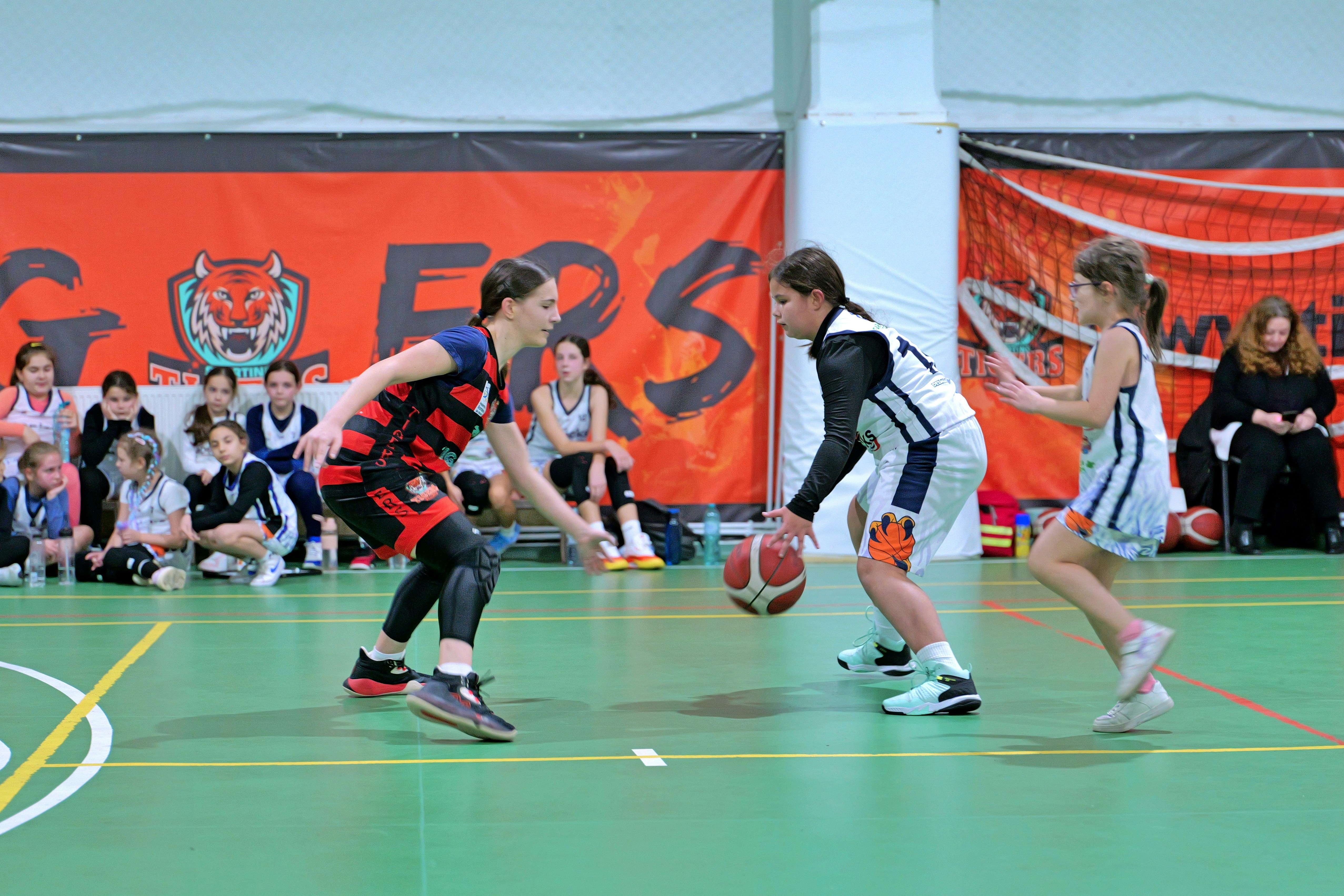 Two young basketball players competing on a green indoor court during a game