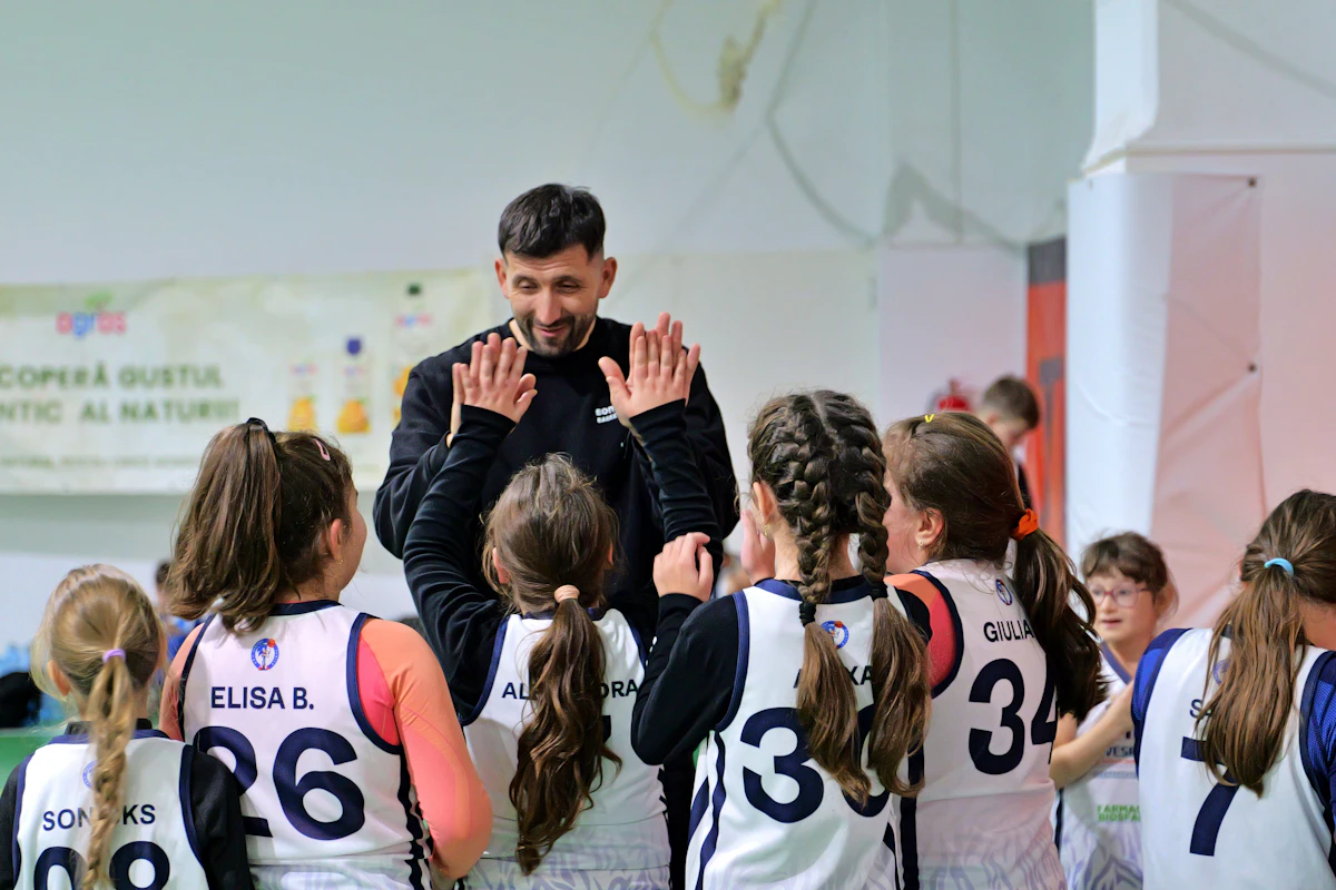 Un entraîneur encourage de jeunes joueuses et joueurs en leur tapant dans la main.
