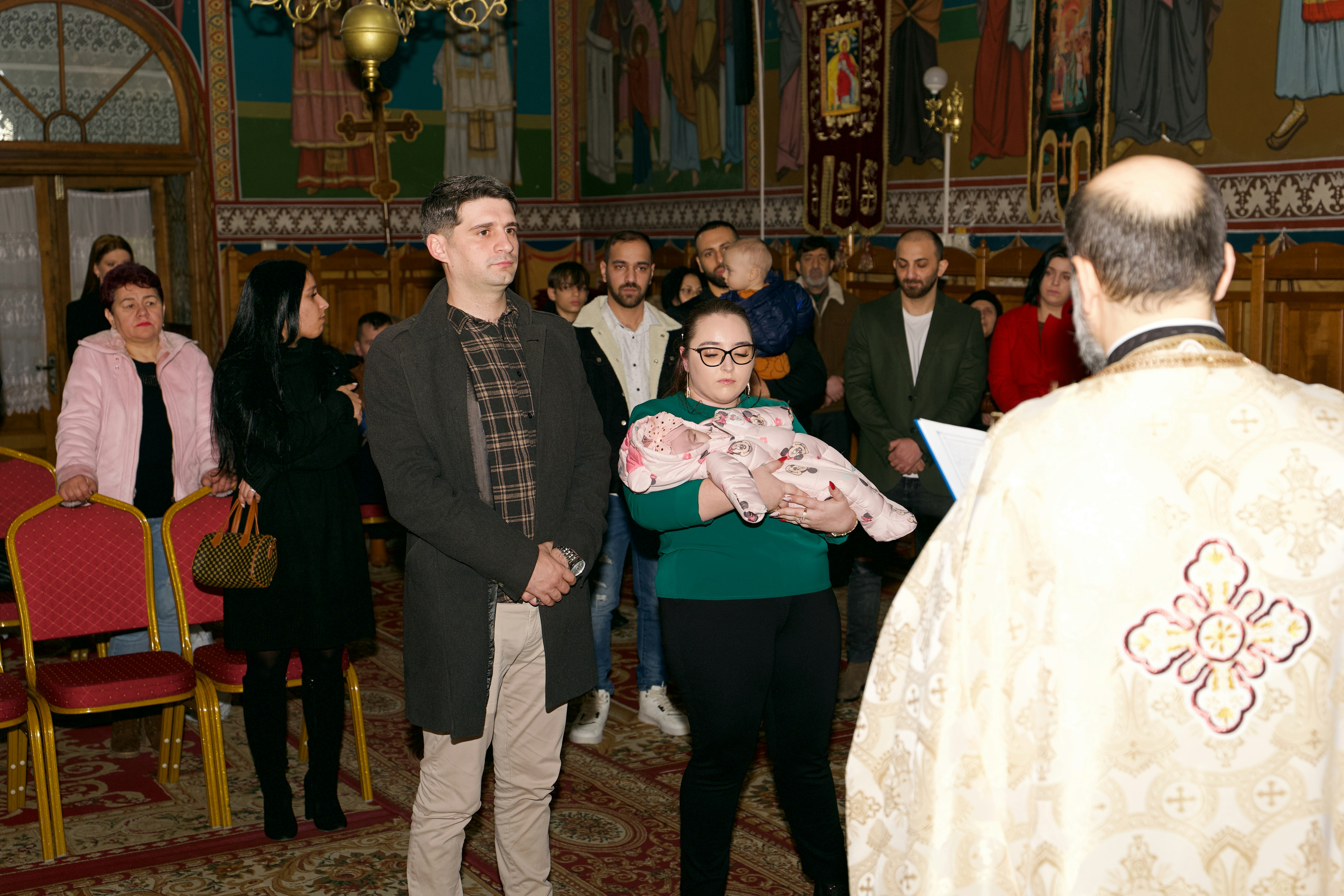 A woman holding a baby during a religious ceremony in a church