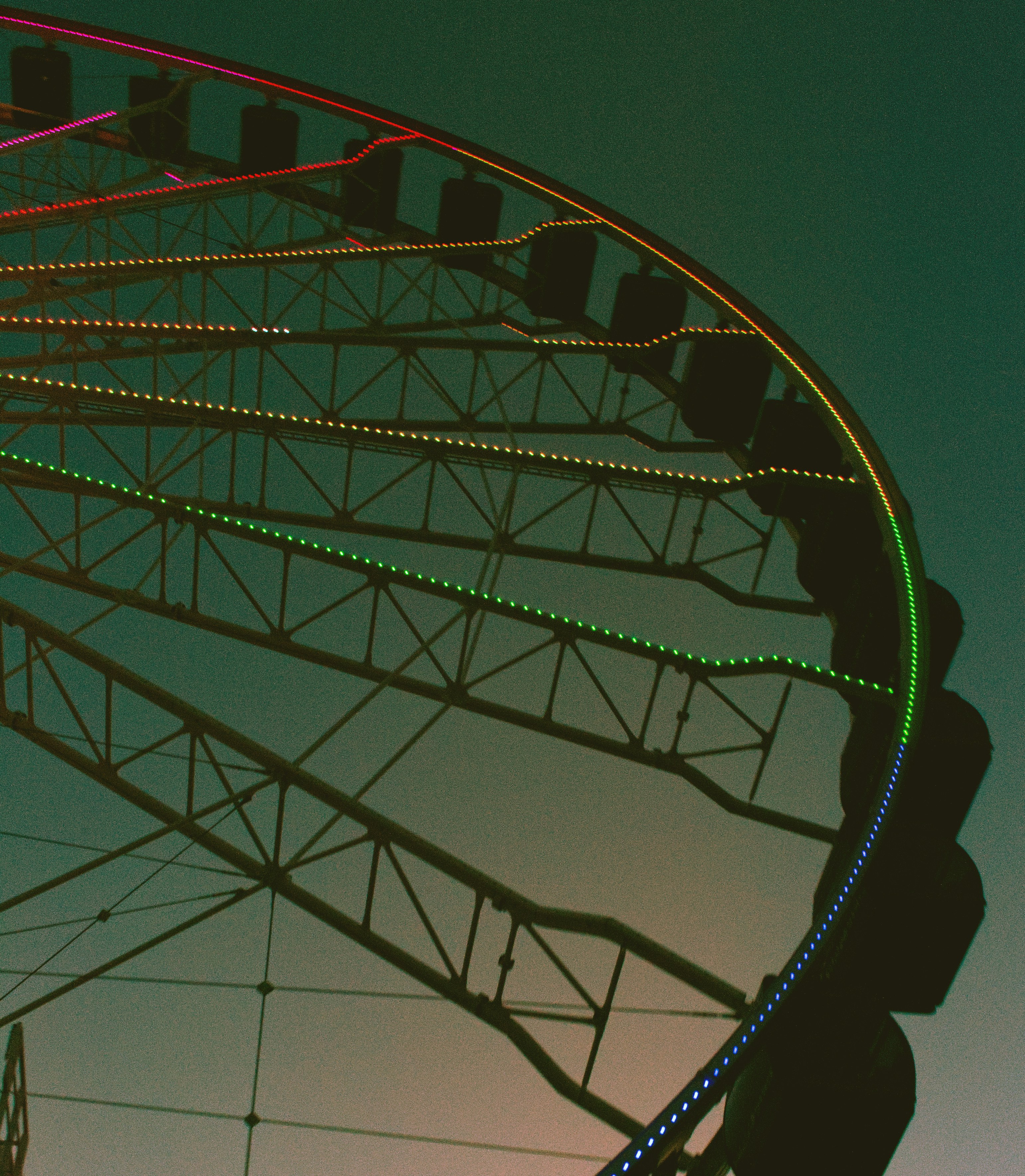 A Ferris wheel with glowing multicolored lights against a dark evening sky