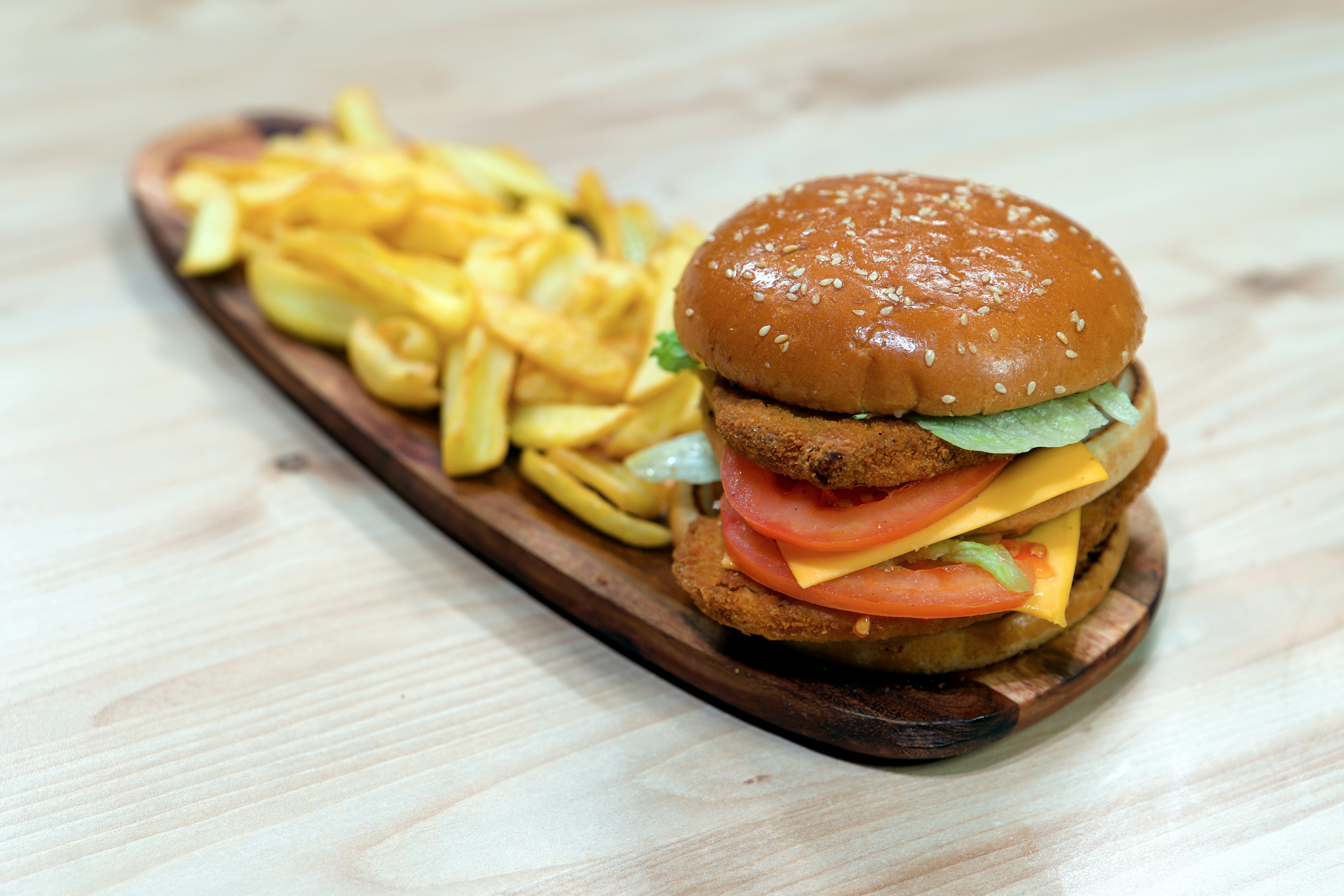 Burger with tomato and fries on a wooden board