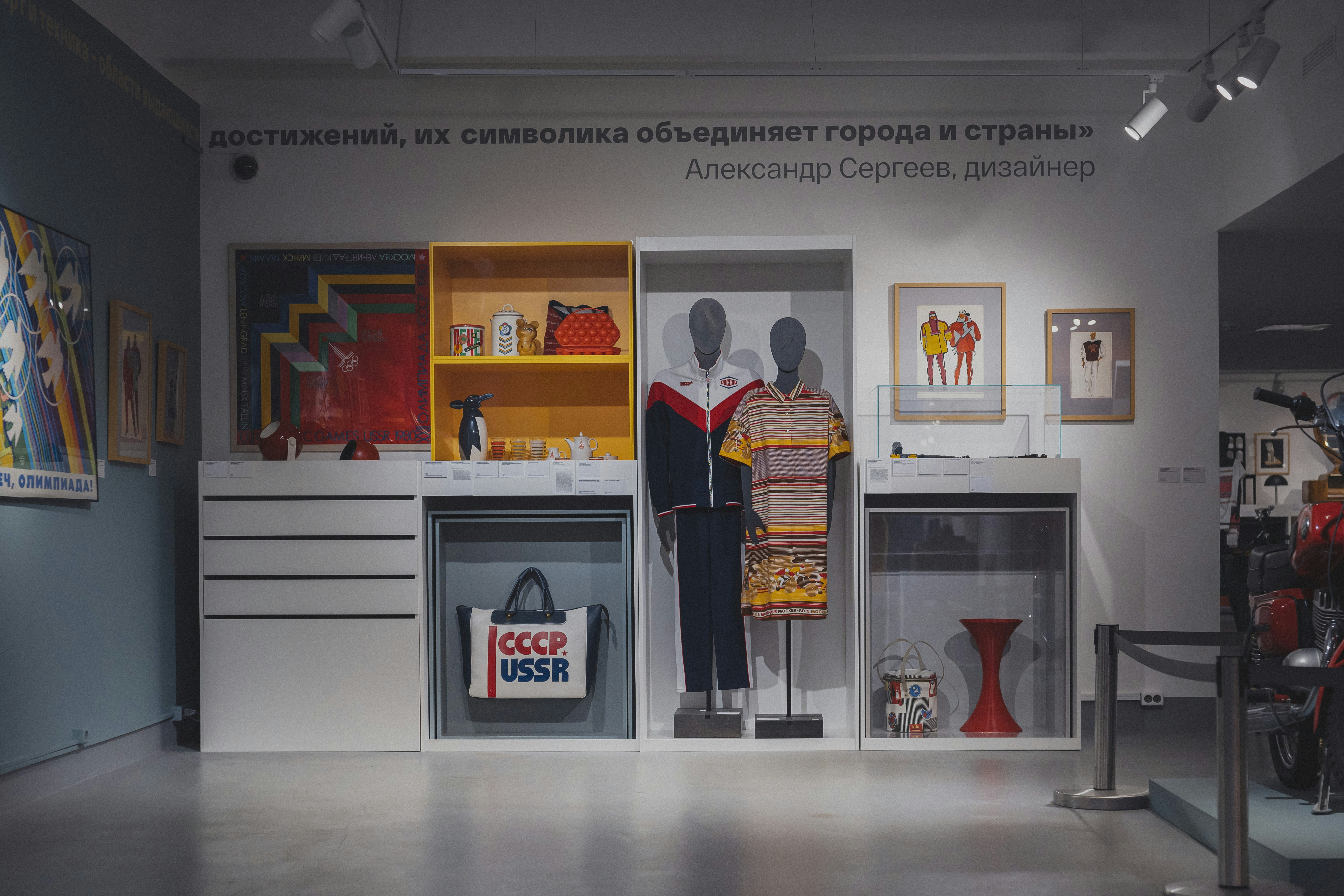Museum display featuring vintage Soviet clothing, a tote bag, and various household objects