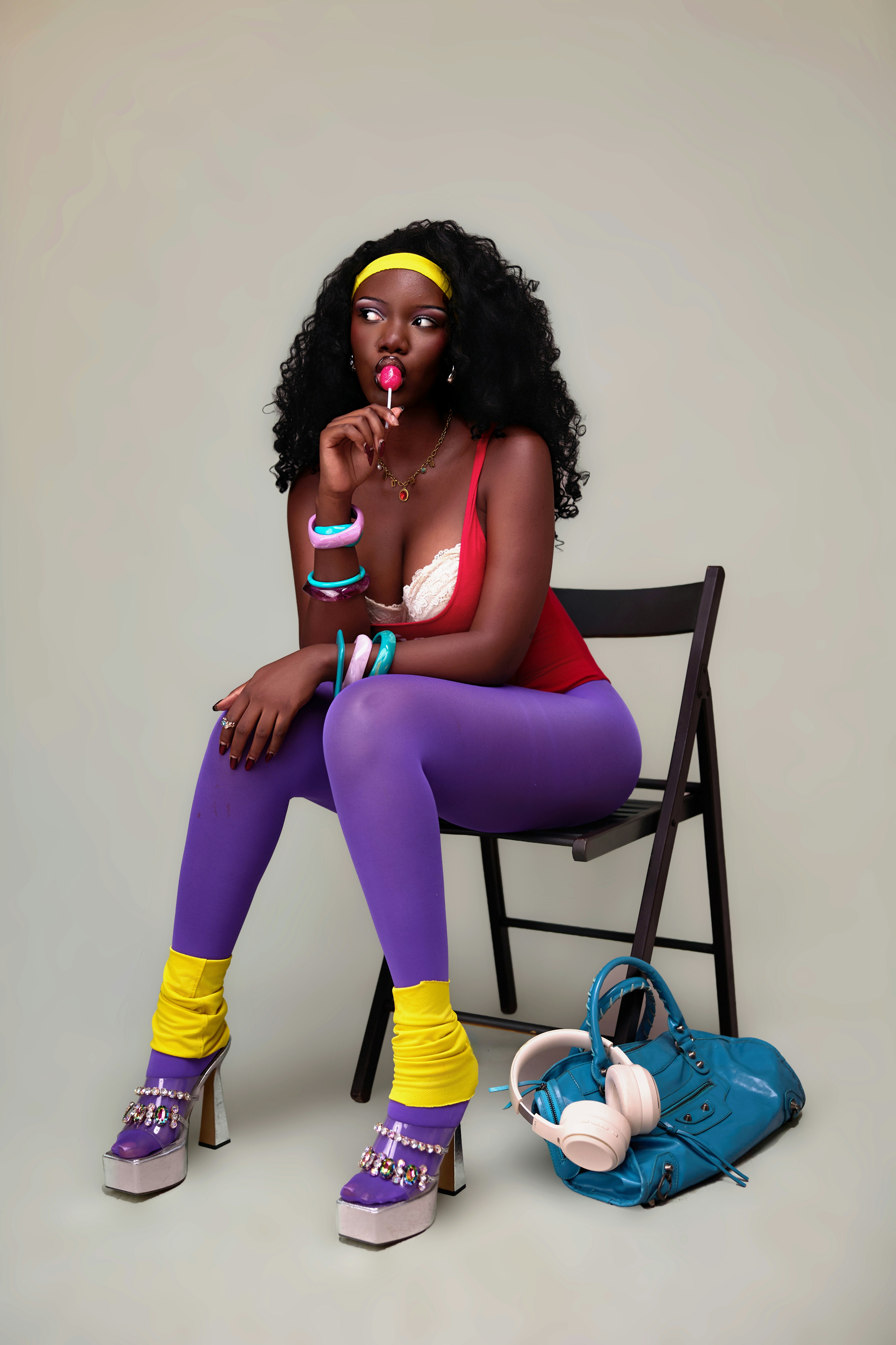 A woman in a red top and purple leggings eating a pink lollipop