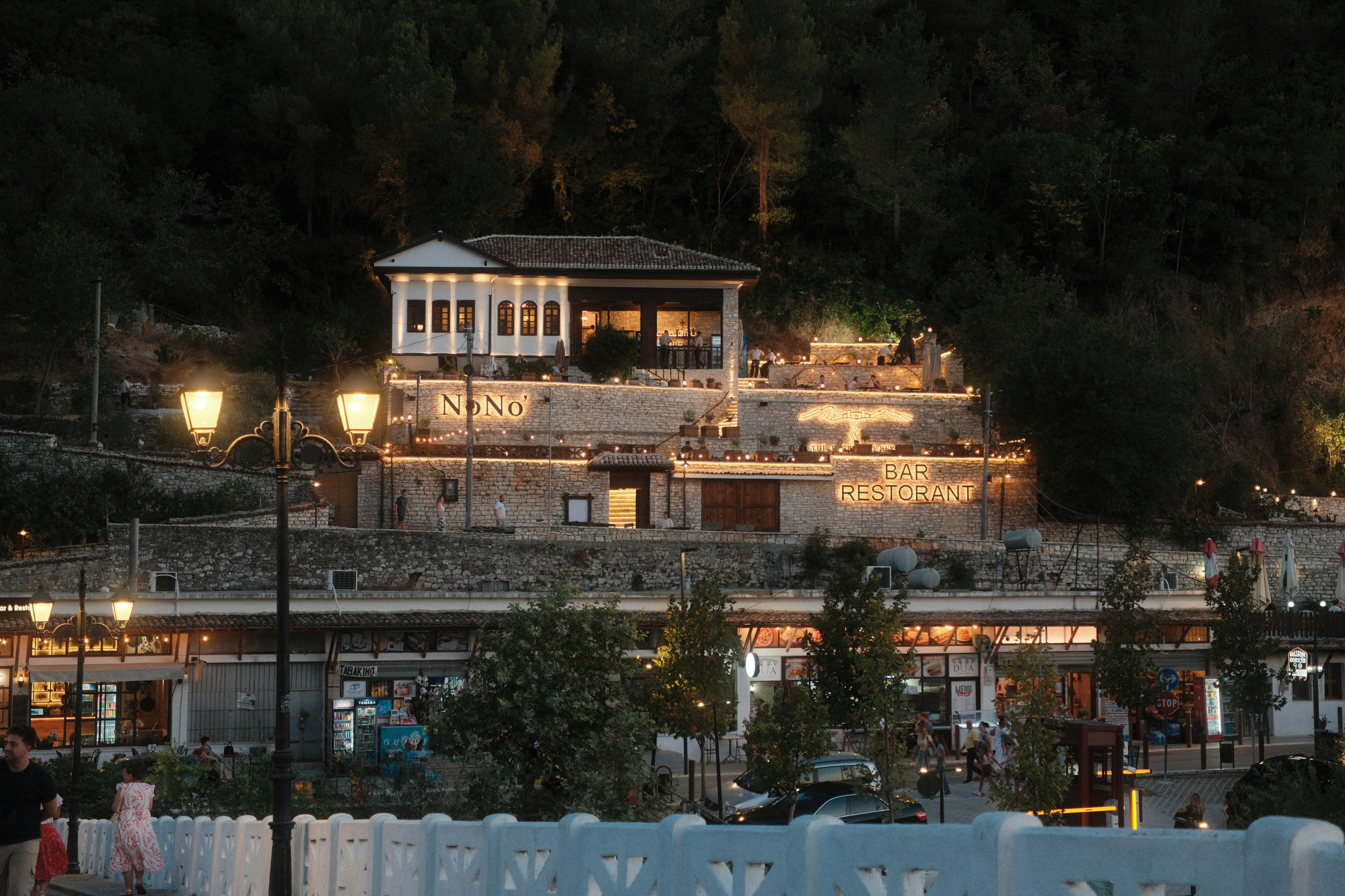 A stone restaurant building with illuminated signage on a hillside at night