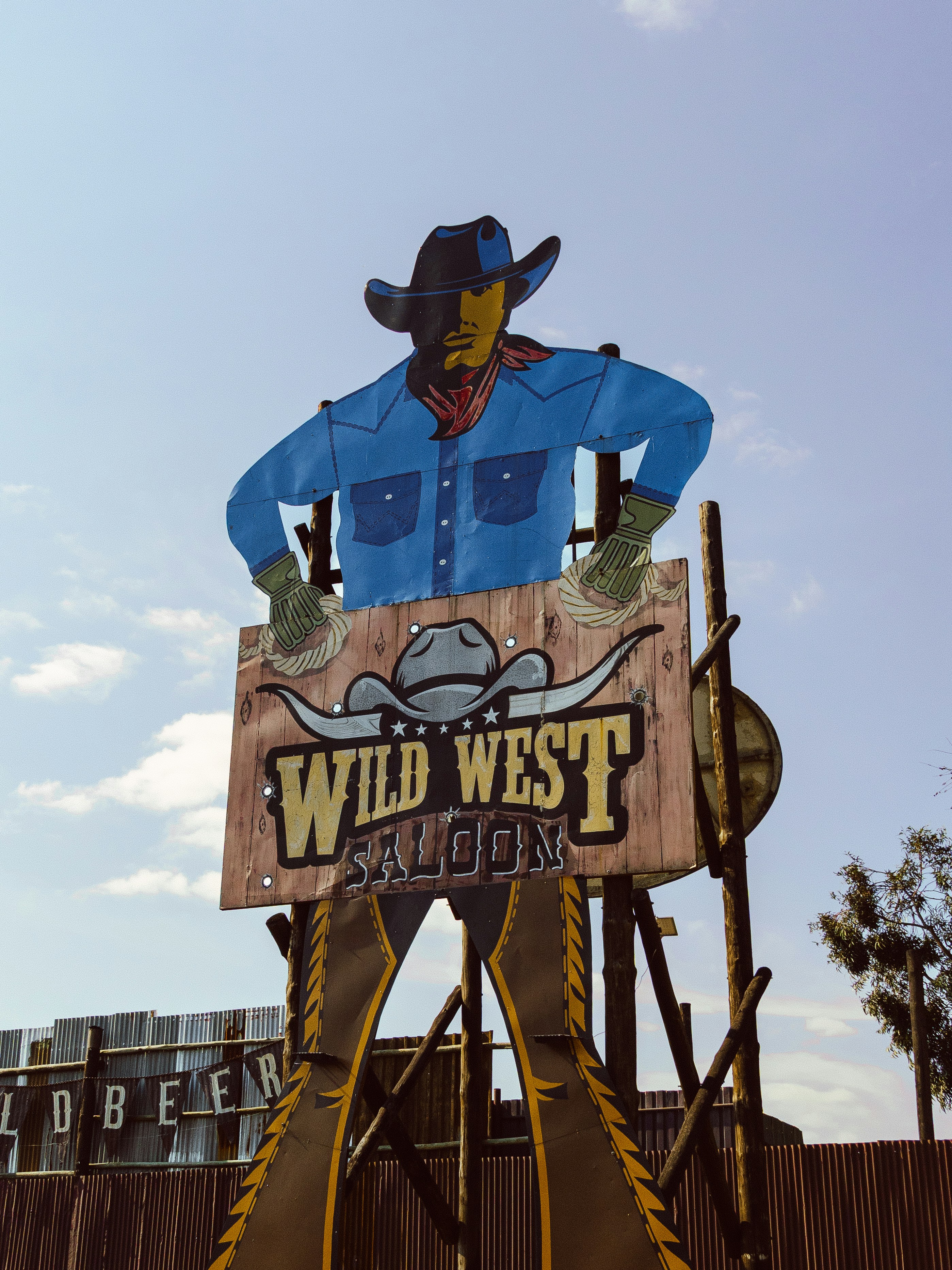 A large cutout sign of a cowboy holding a Wild West Saloon sign