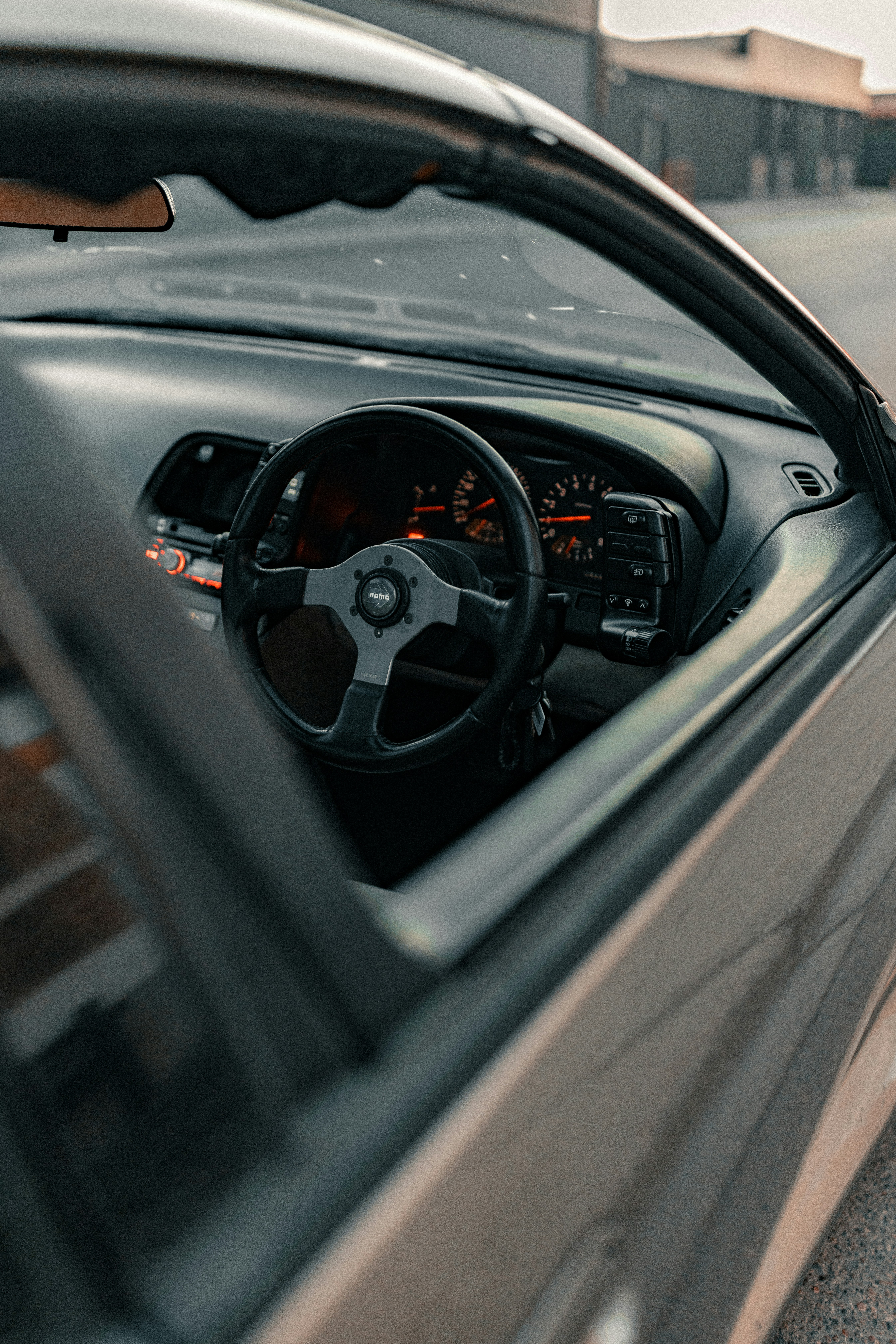 A black aftermarket steering wheel inside a car with illuminated dashboard gauges