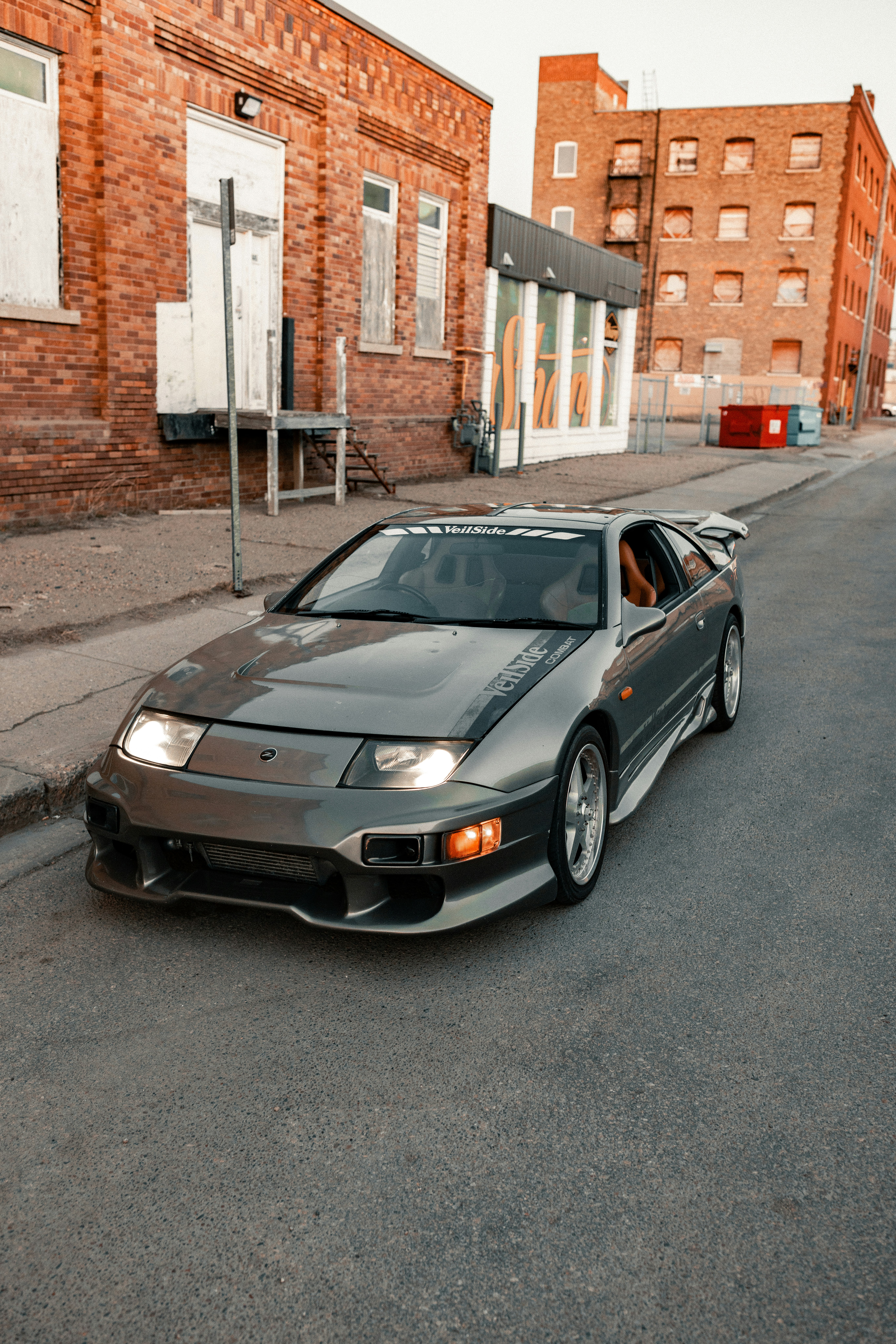 A grey Nissan 300ZX sports car parked on a city street at golden hour