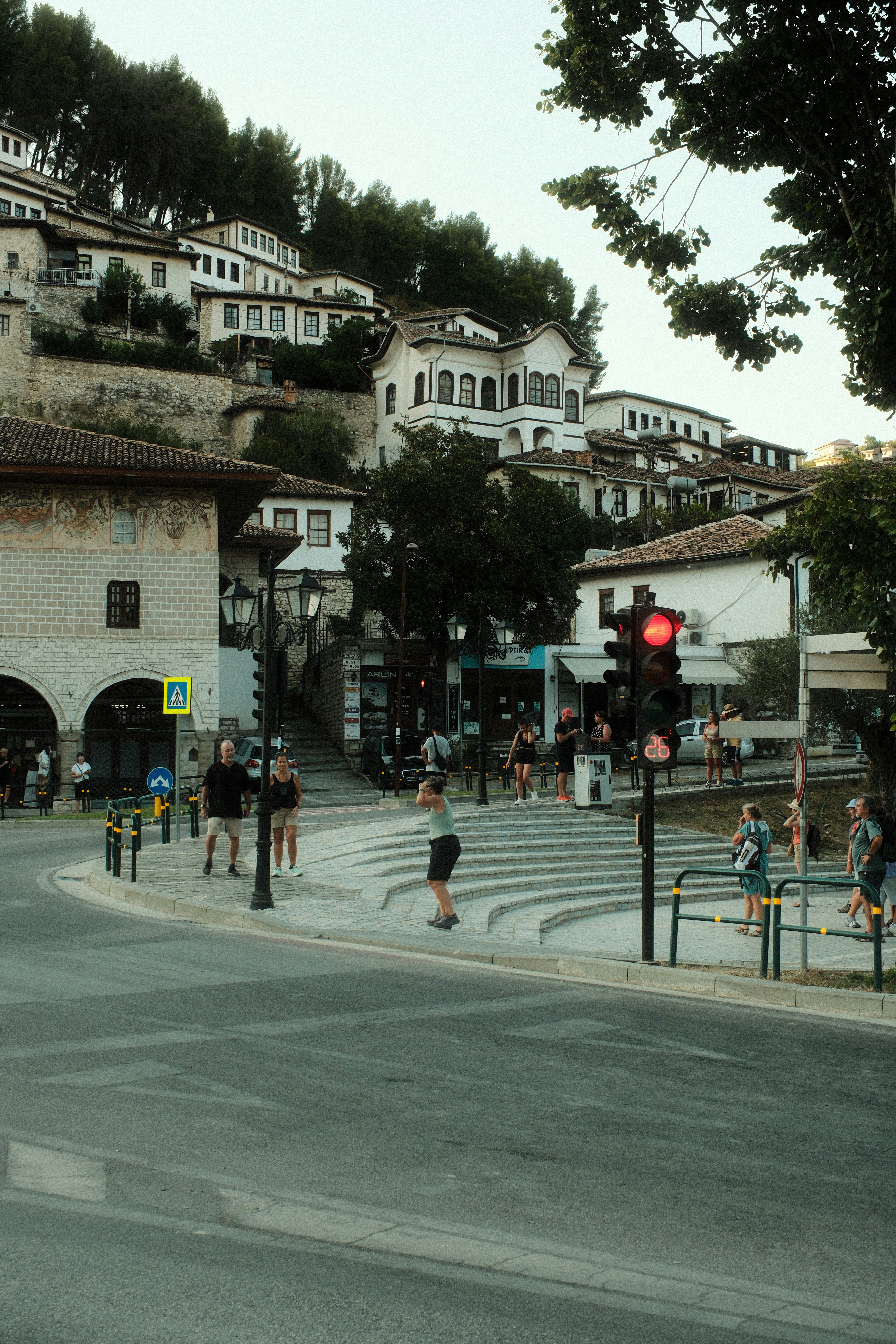 People walking near a red traffic light in the historic town of Berat