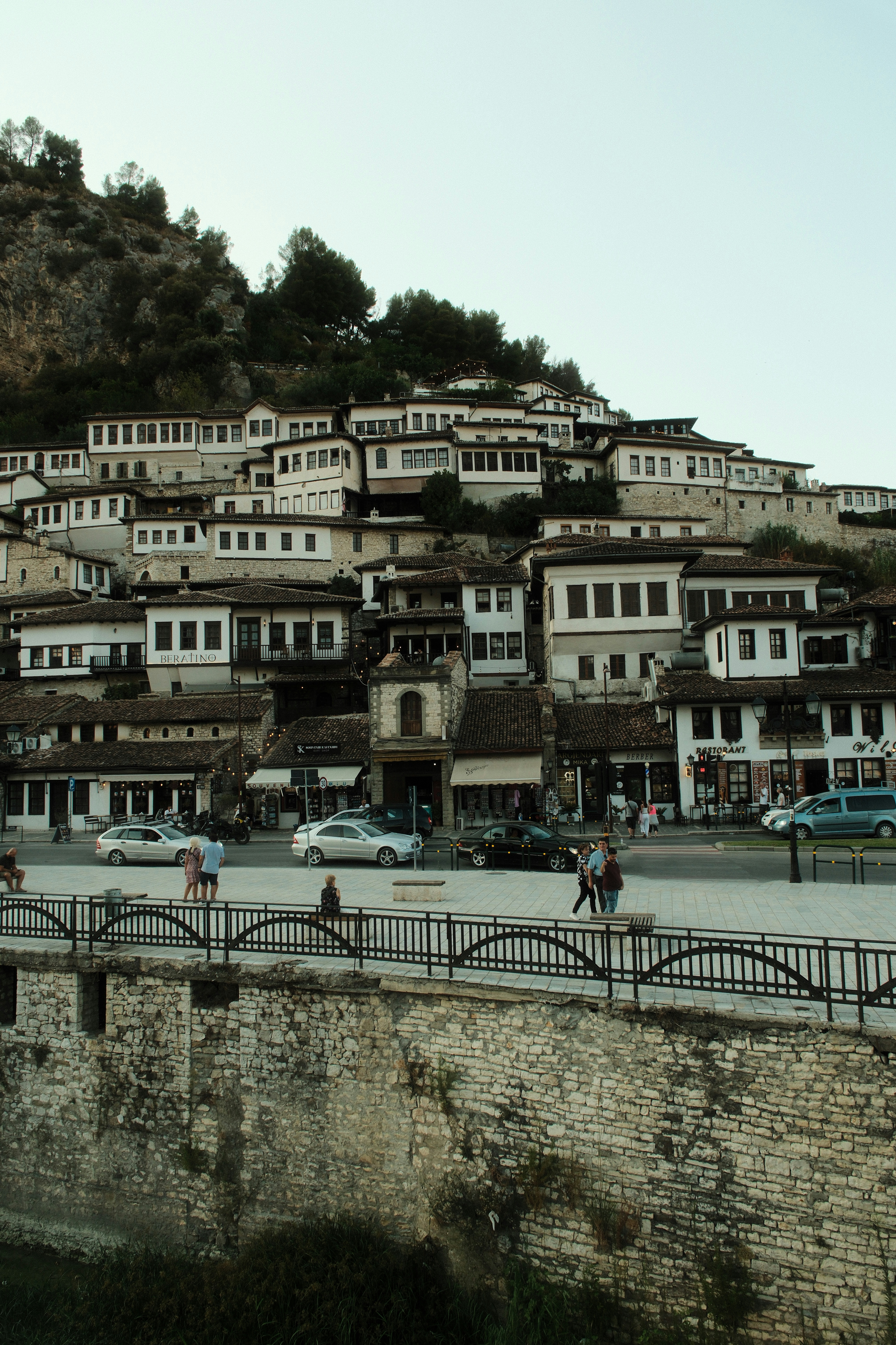 White houses with dark roofs stacked on a hillside above a city street