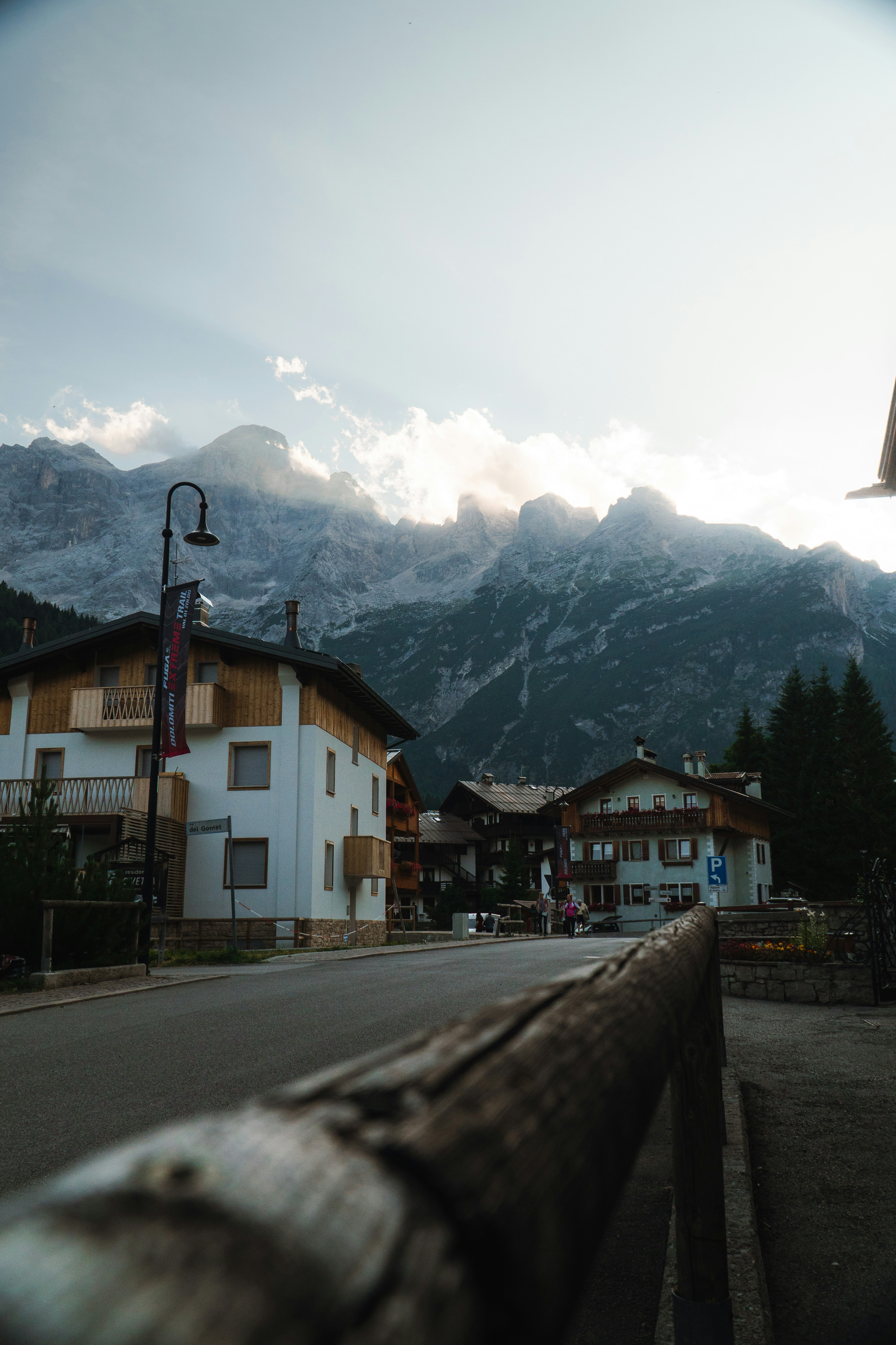 A quiet street in a mountain village with wooden houses below jagged peaks