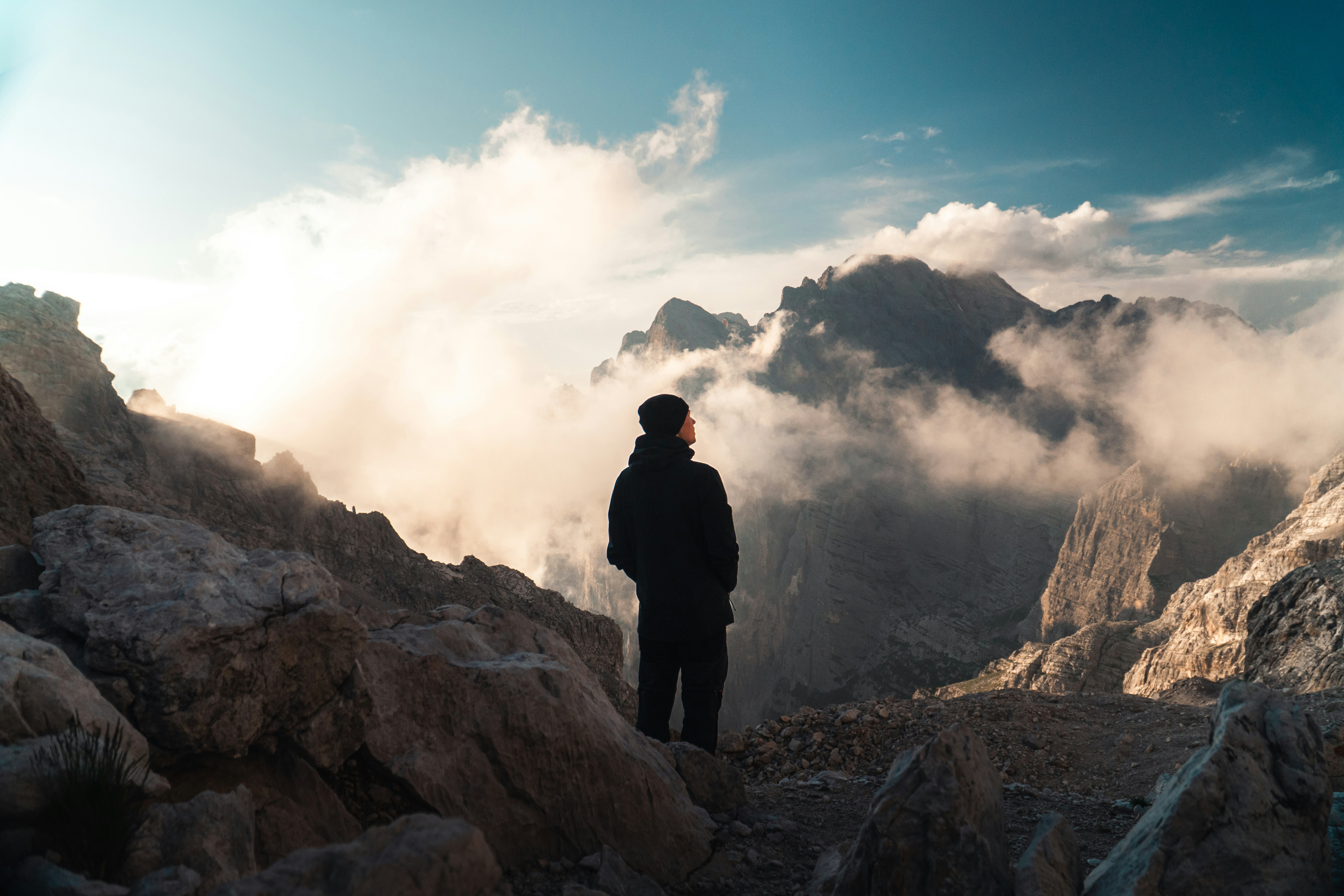 A person in a dark jacket and beanie on a rocky mountain ridge