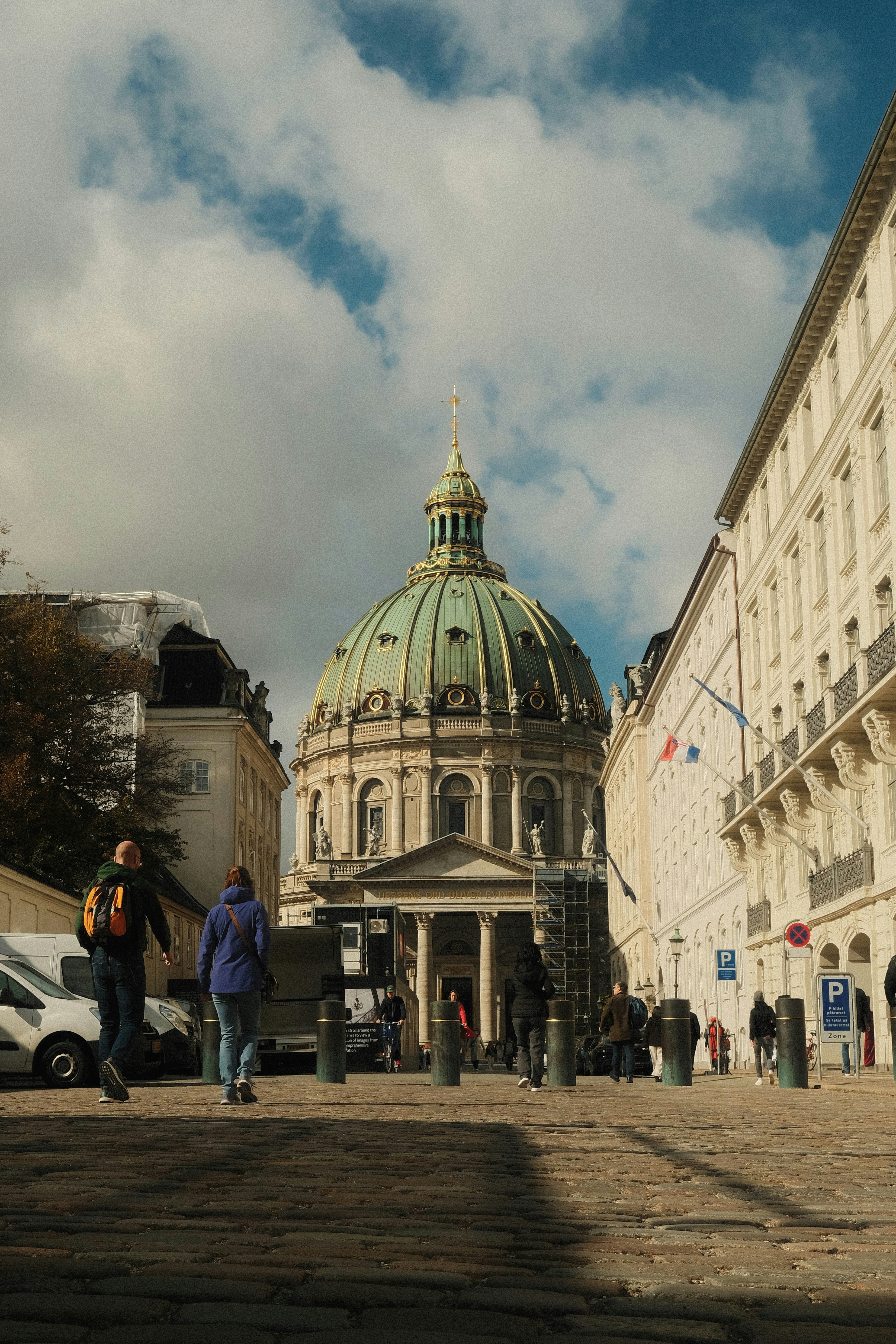 People walking on a cobblestone street toward the Frederik's Church dome in Copenhagen
