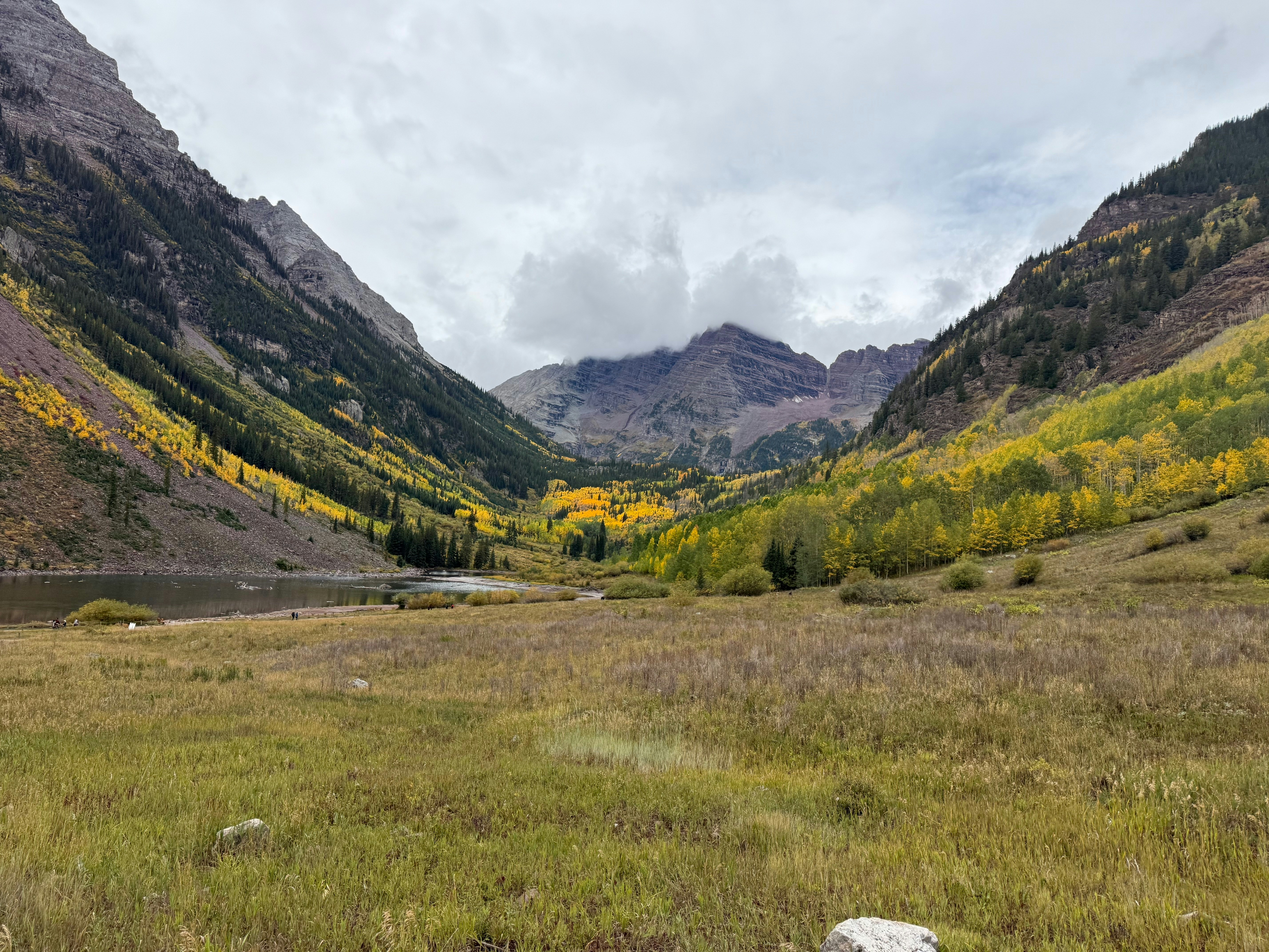 Maroon Bells mountains above a lake with yellow autumn aspen trees in Colorado