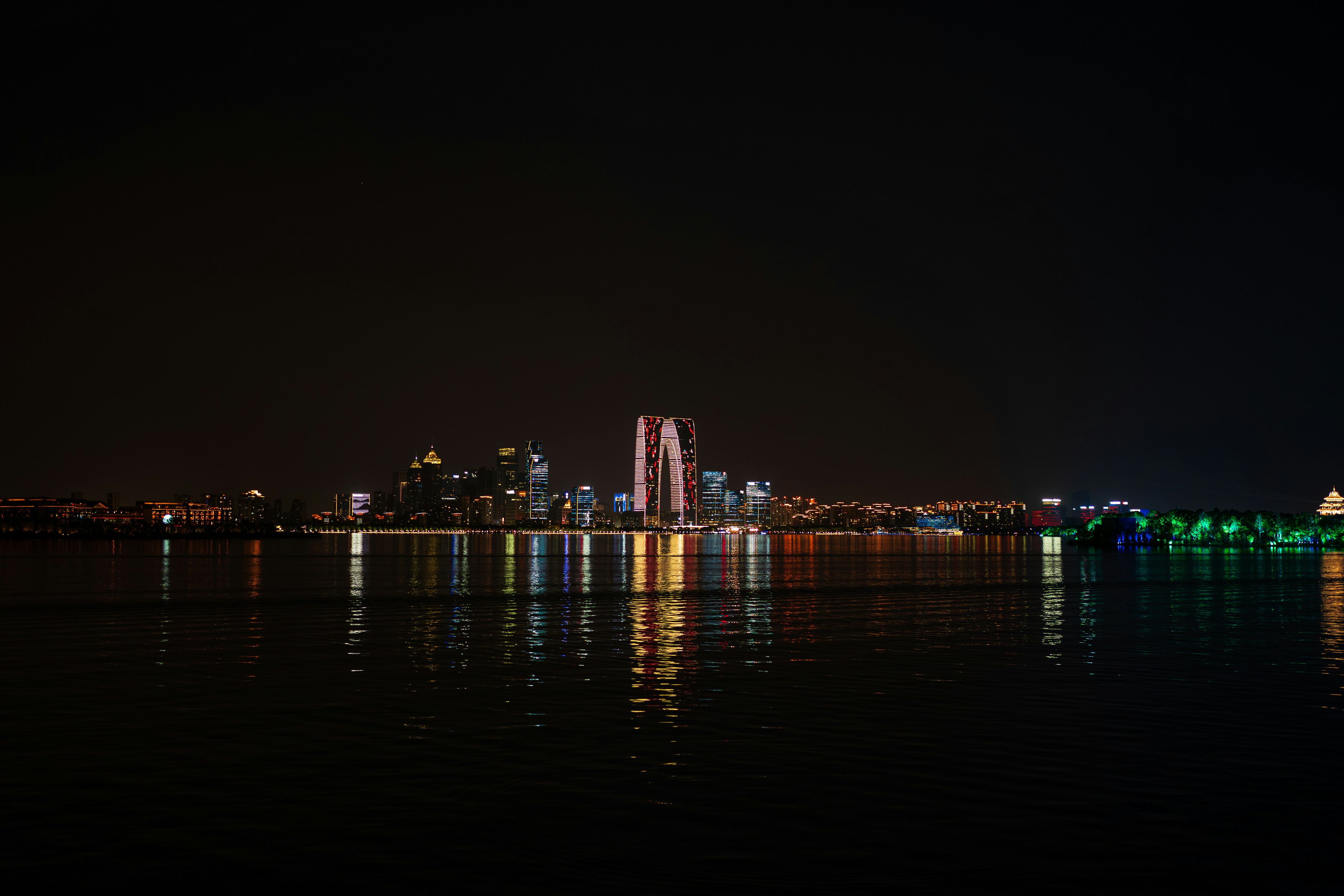 The illuminated skyline of Suzhou reflected in the dark waters of Jinji Lake
