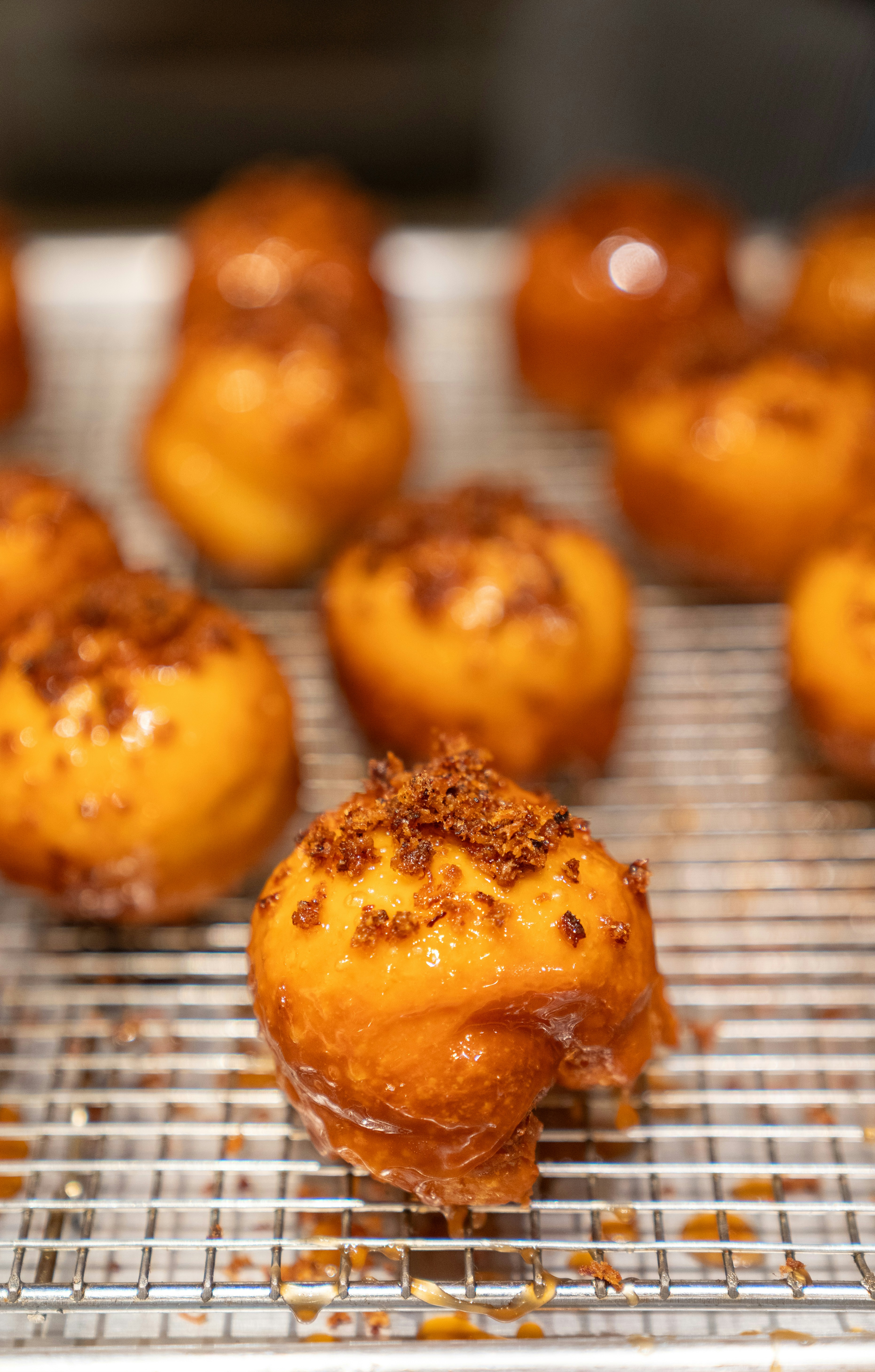 Glazed golden brown donut holes topped with brown sugar on a wire rack