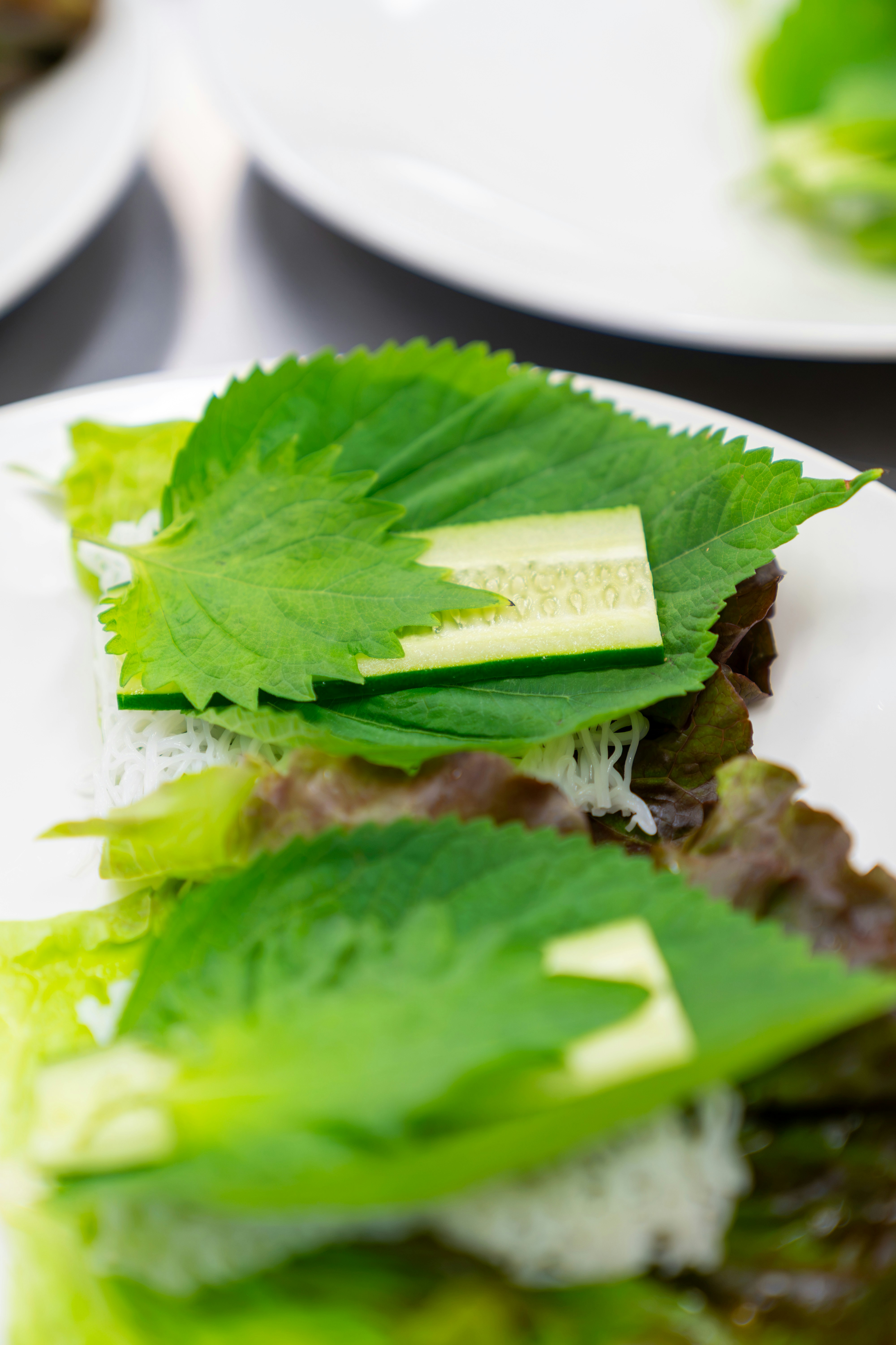 Perilla leaves with cucumber slices and rice noodles on a white plate
