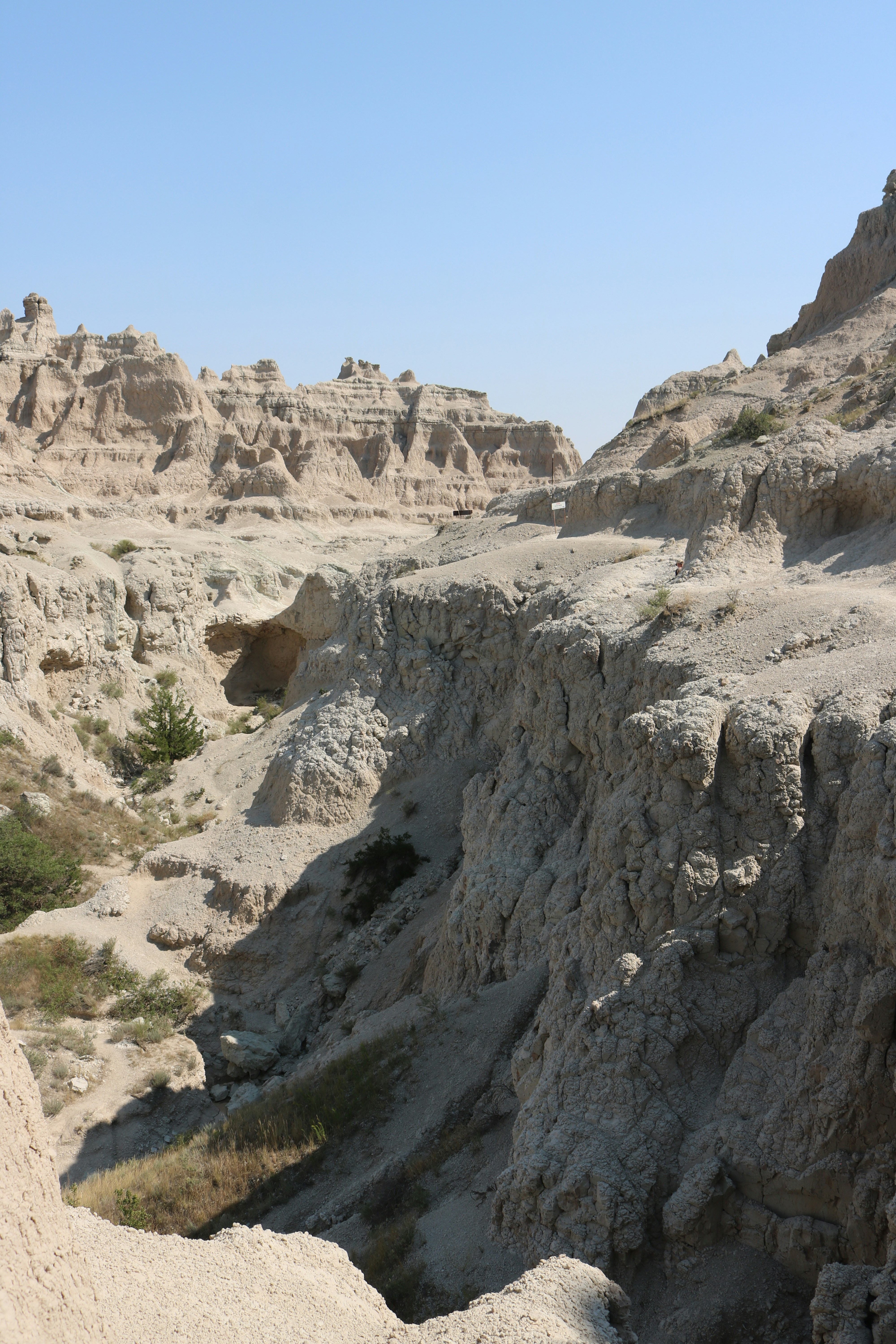 Eroded rock formations and steep canyons in Badlands National Park under a clear sky