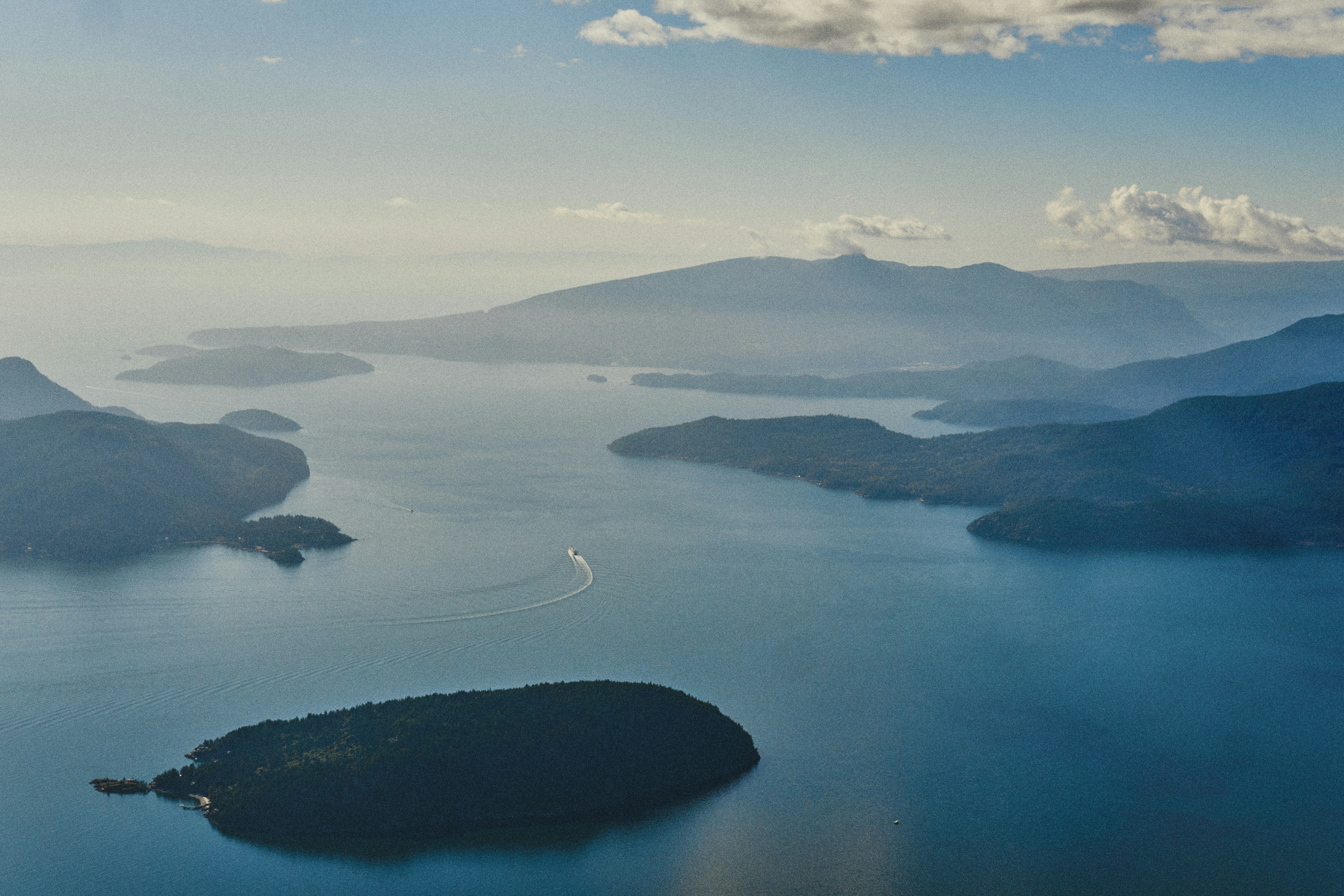 An aerial view of islands in a blue bay with a boat leaving a wake