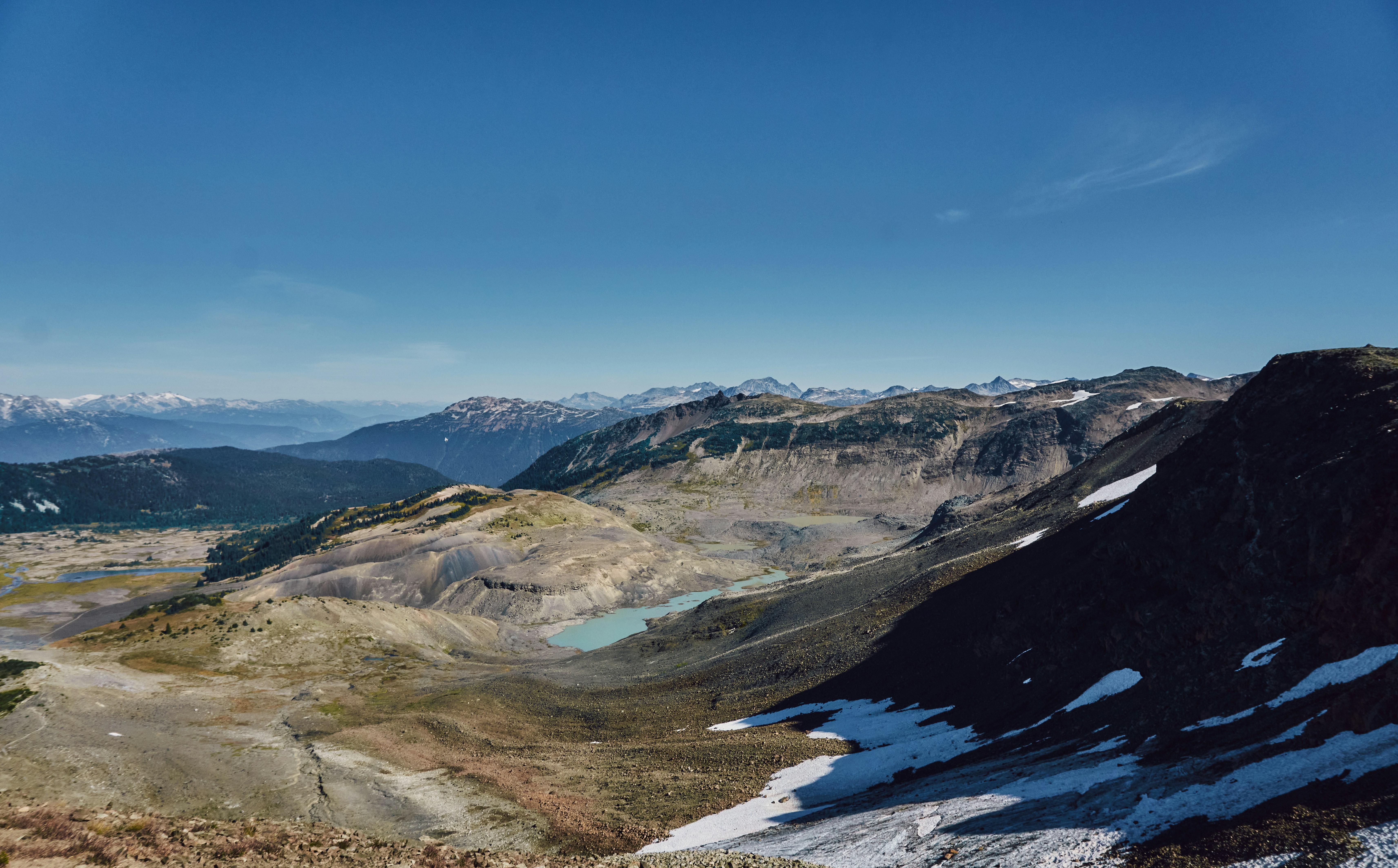 A turquoise glacial lake in a vast mountain valley under a clear blue sky