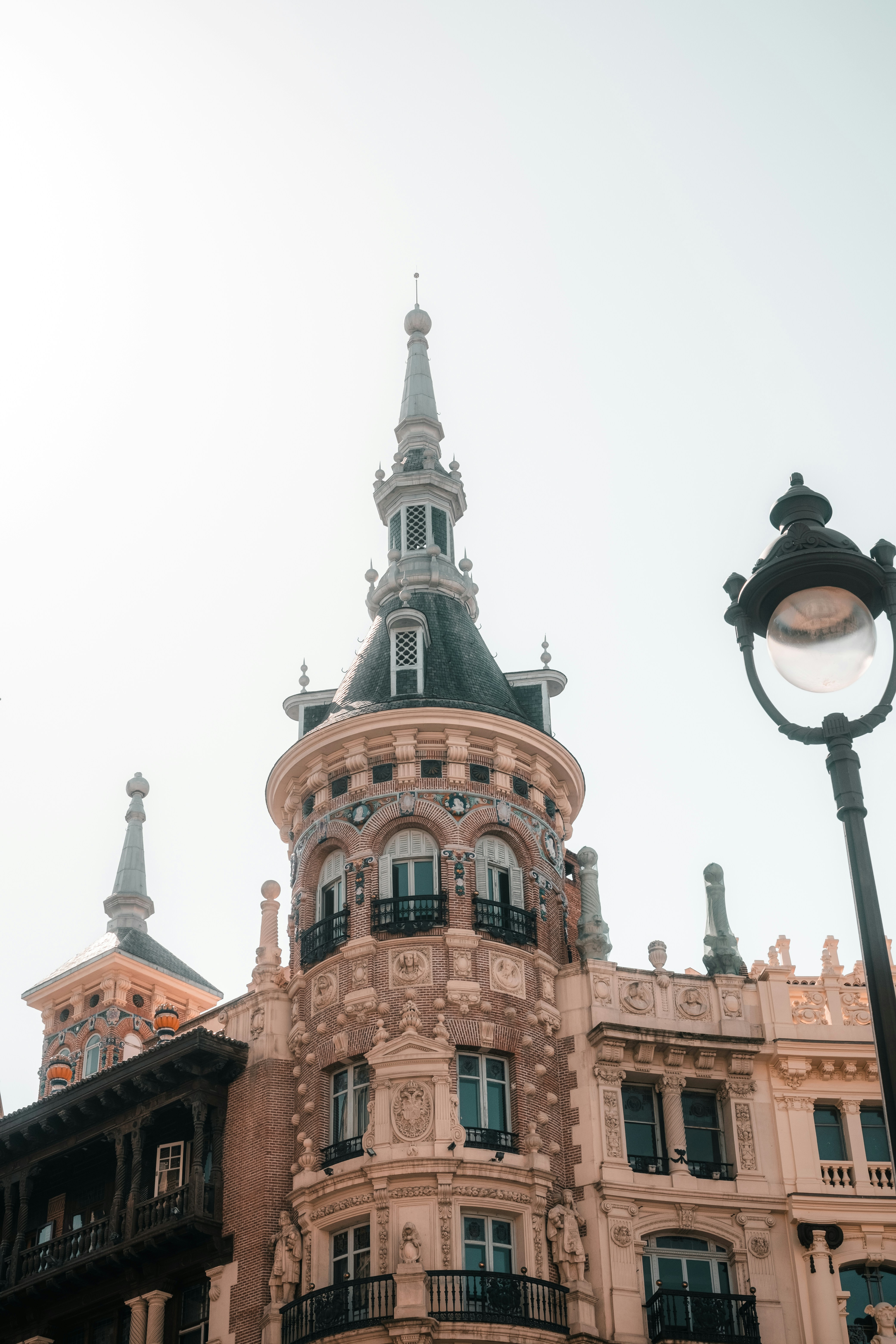 Ornate brick tower with a spire and balconies against a bright sky