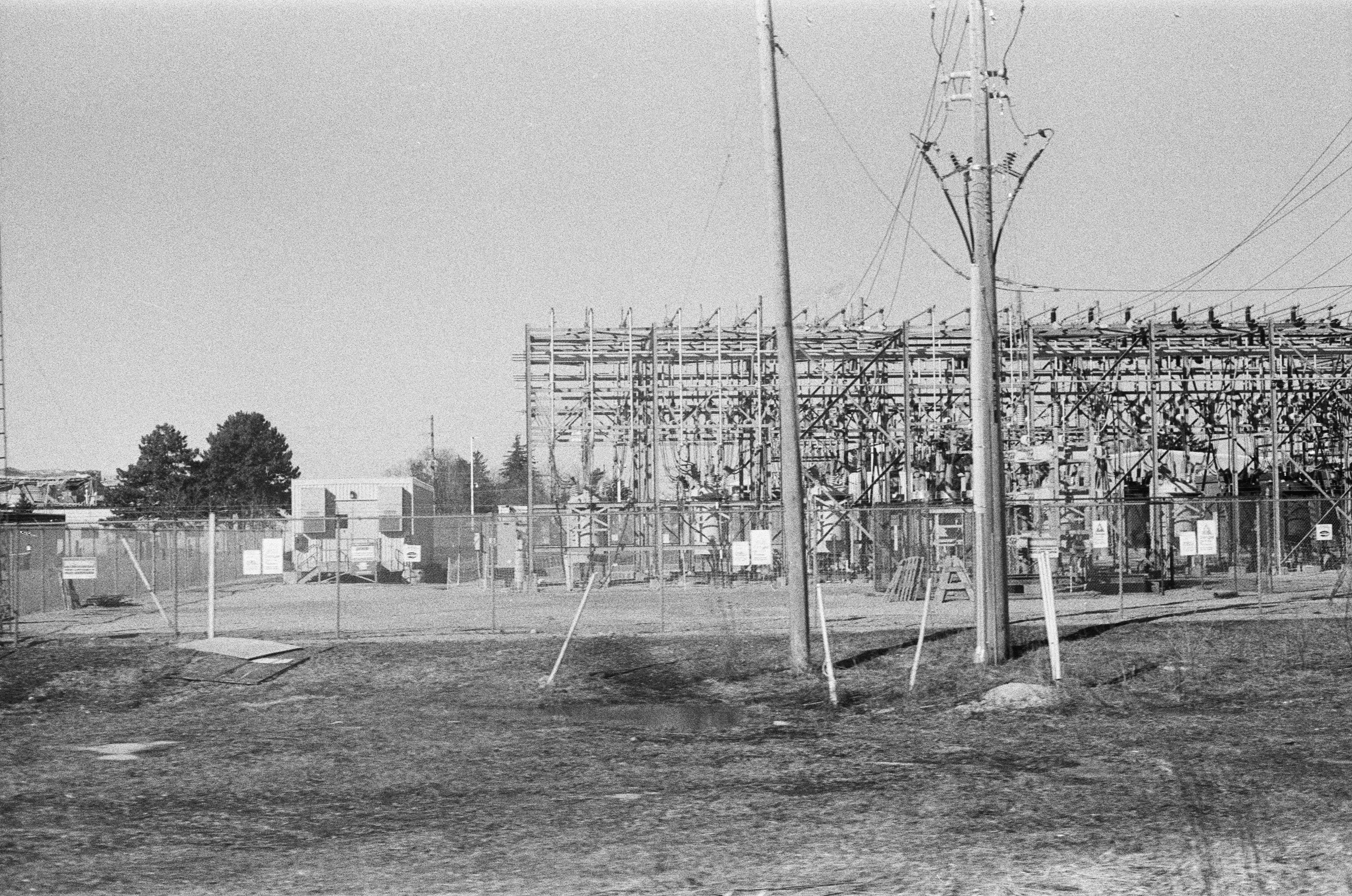 An electrical substation with metal structures and power lines behind a chain link fence