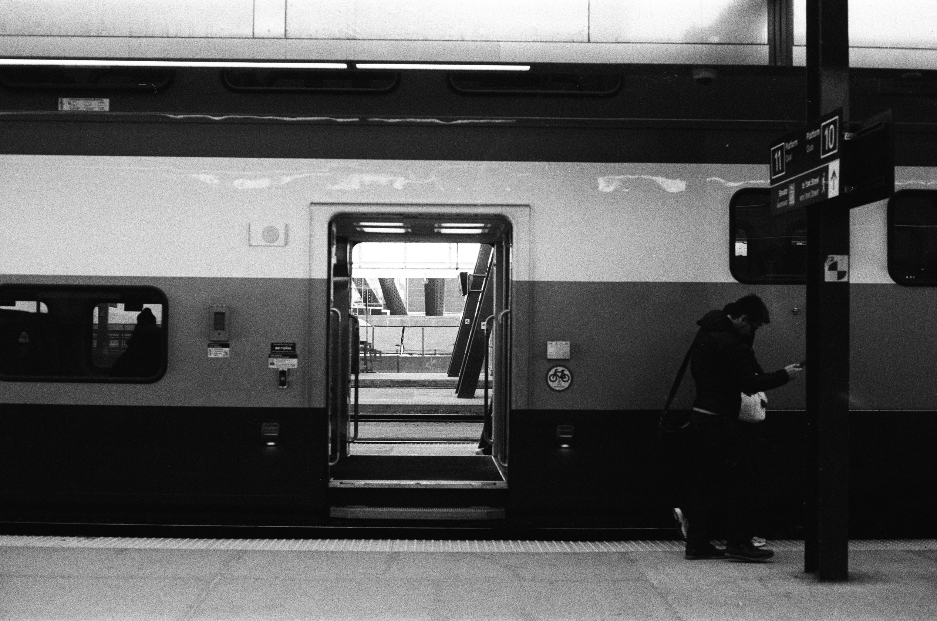 Black and white photo of a person beside train doors