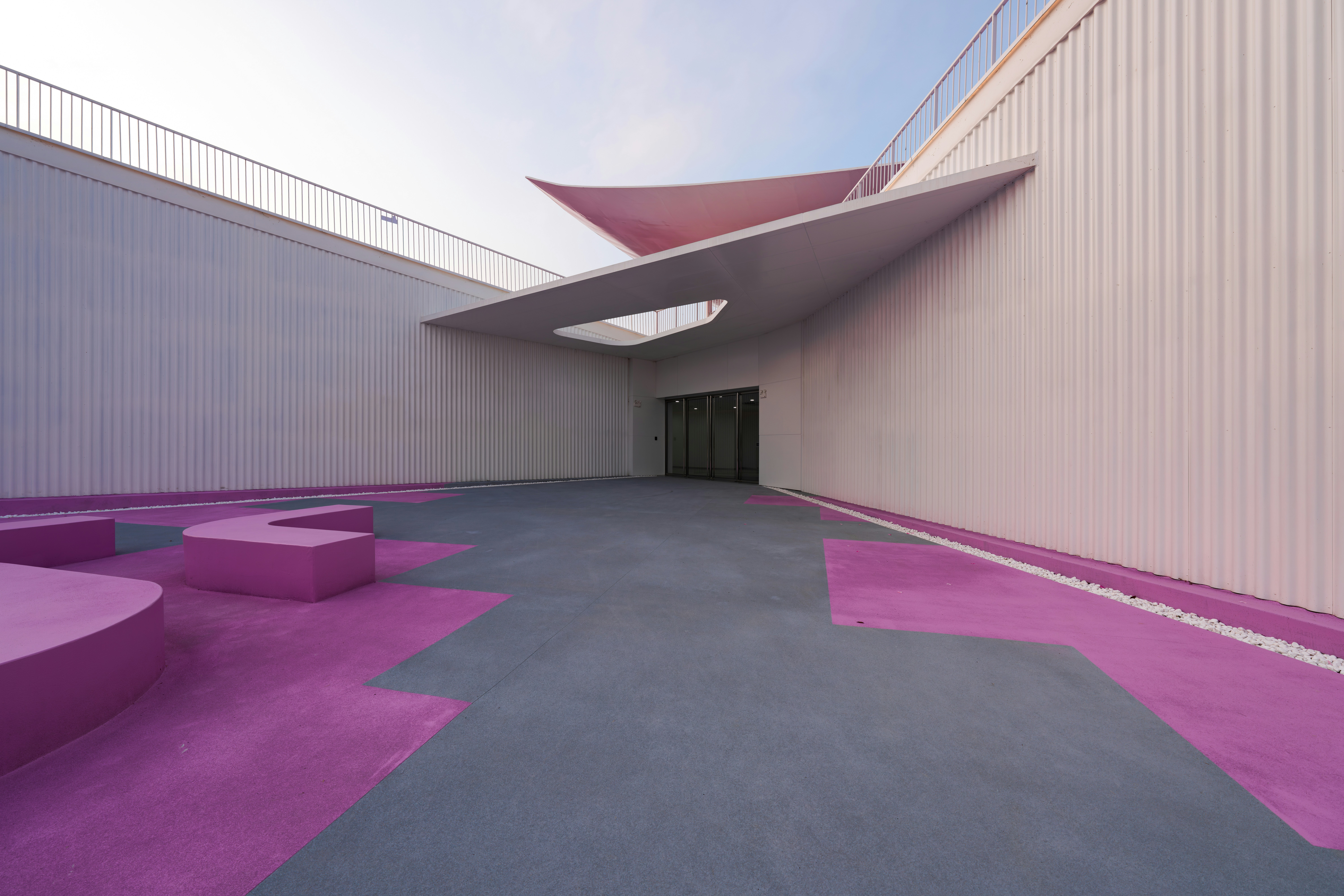Un patio moderno con suelos geométricos grises y morados y paredes corrugadas blancas