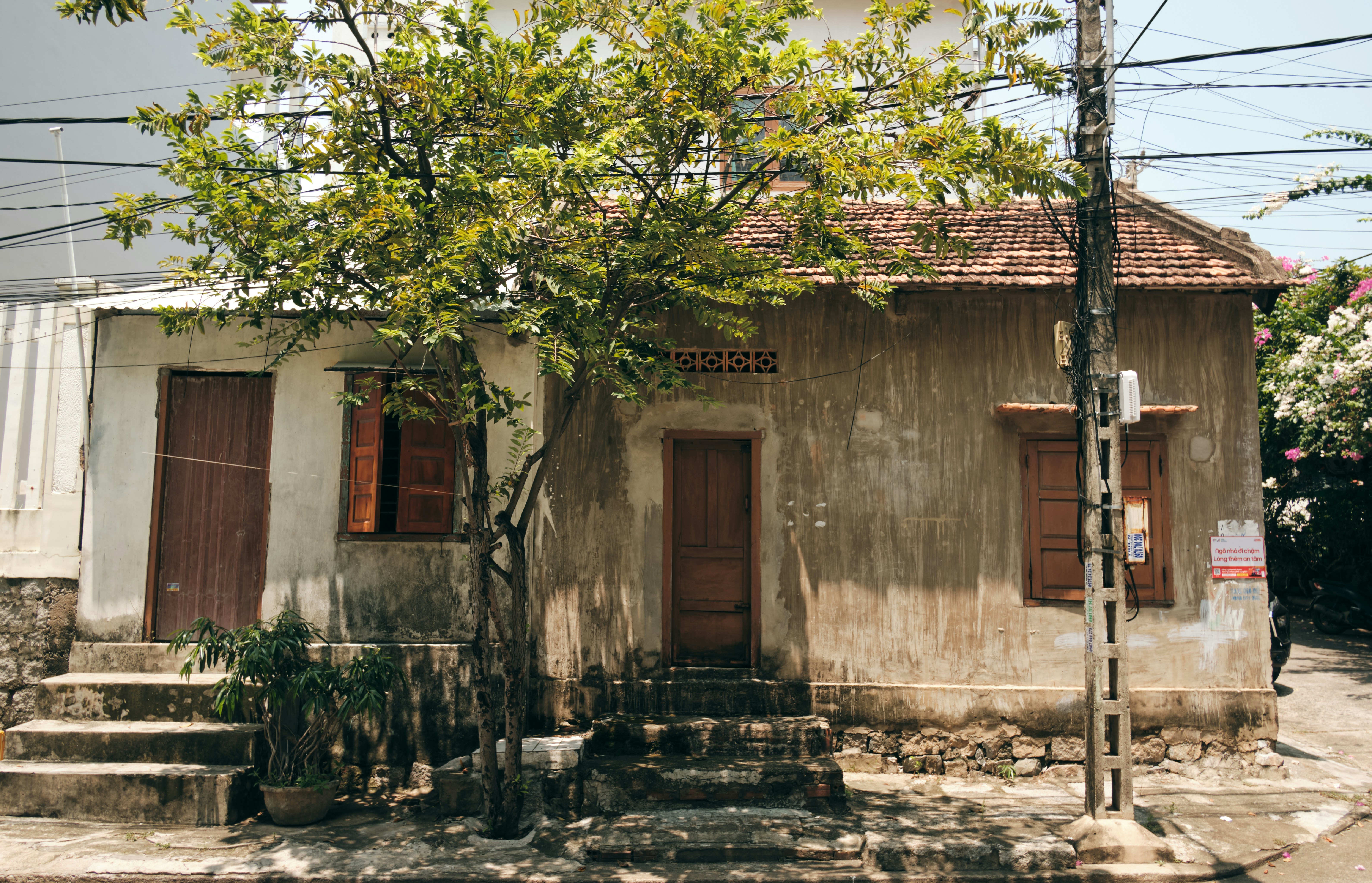 A house with wooden doors and a tiled roof beside a tree