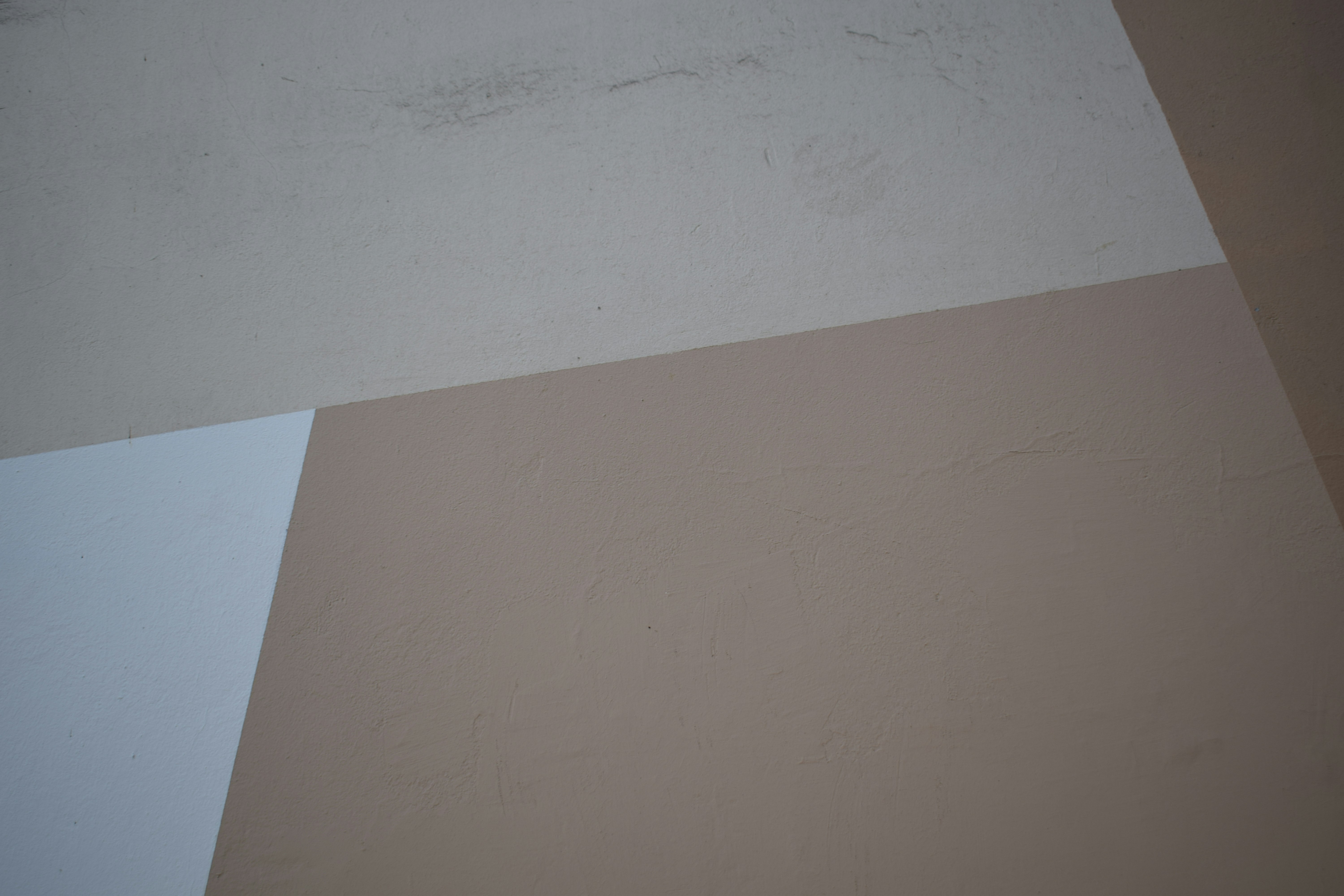 Geometric shapes in white and beige on a textured plaster wall