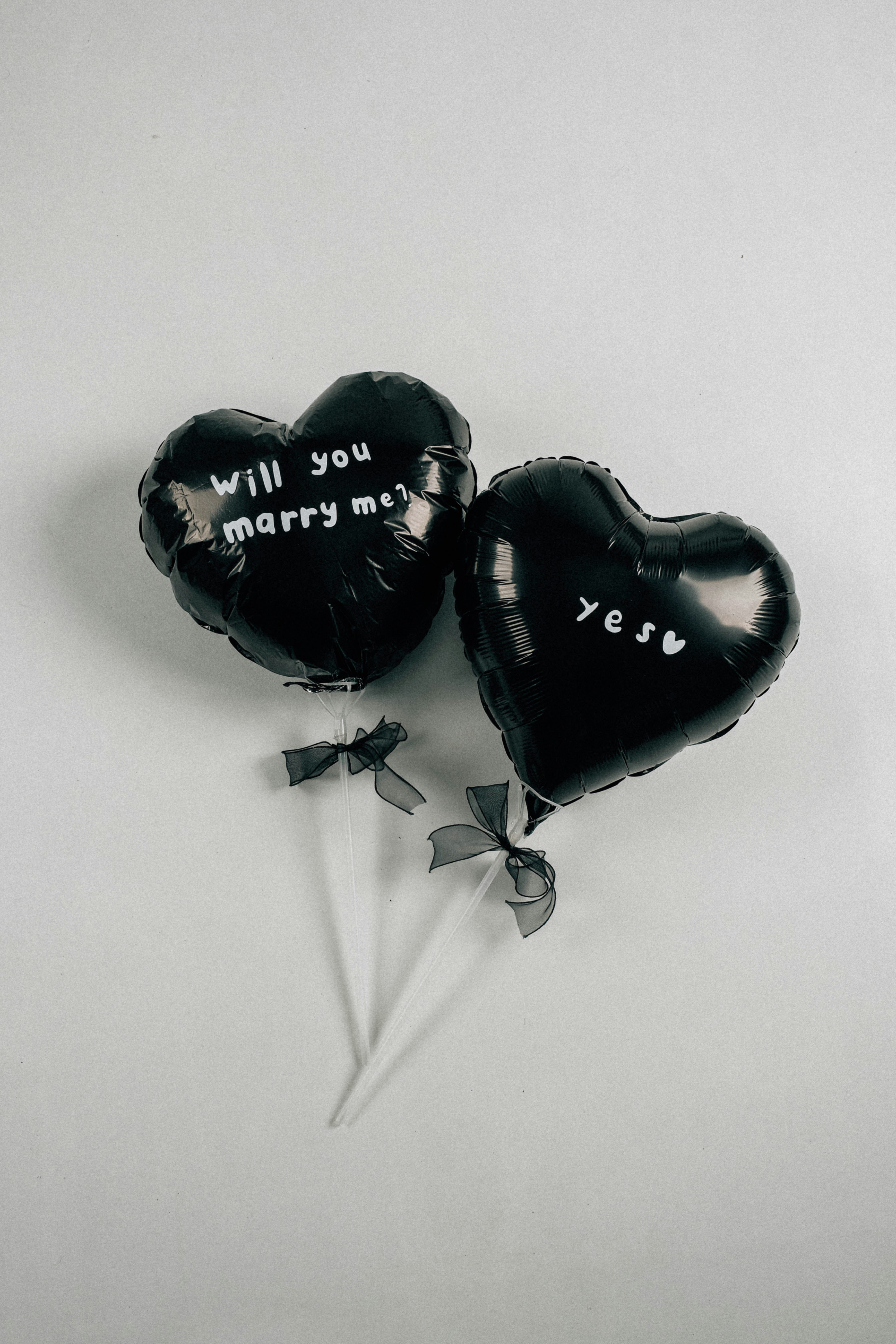 Two black heart balloons with ribbons reading "Will you marry me?" and "yes" - 相关推荐