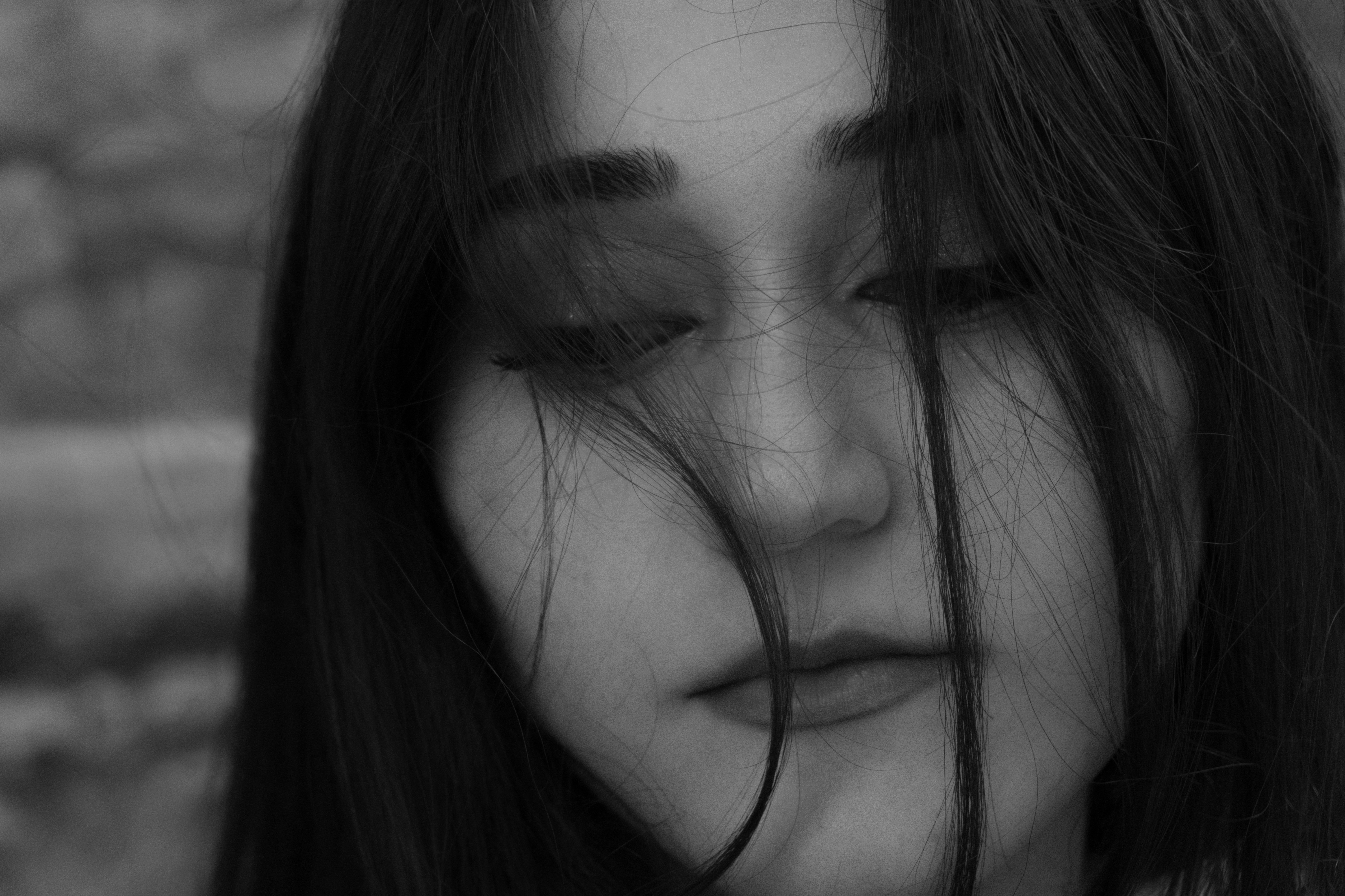 A woman with dark hair falling across her face in a black and white portrait