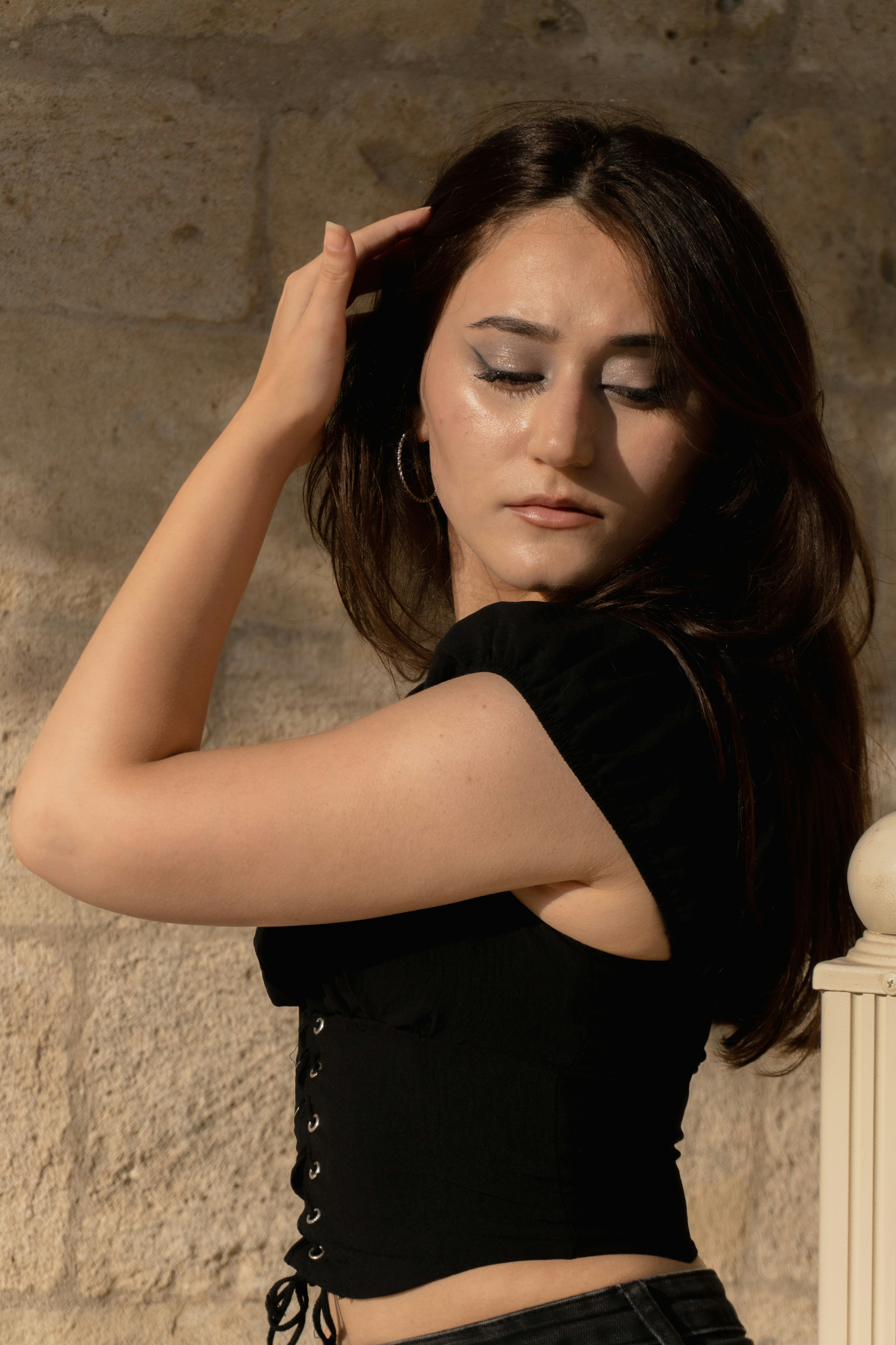 A woman in a black top with her hand in her hair