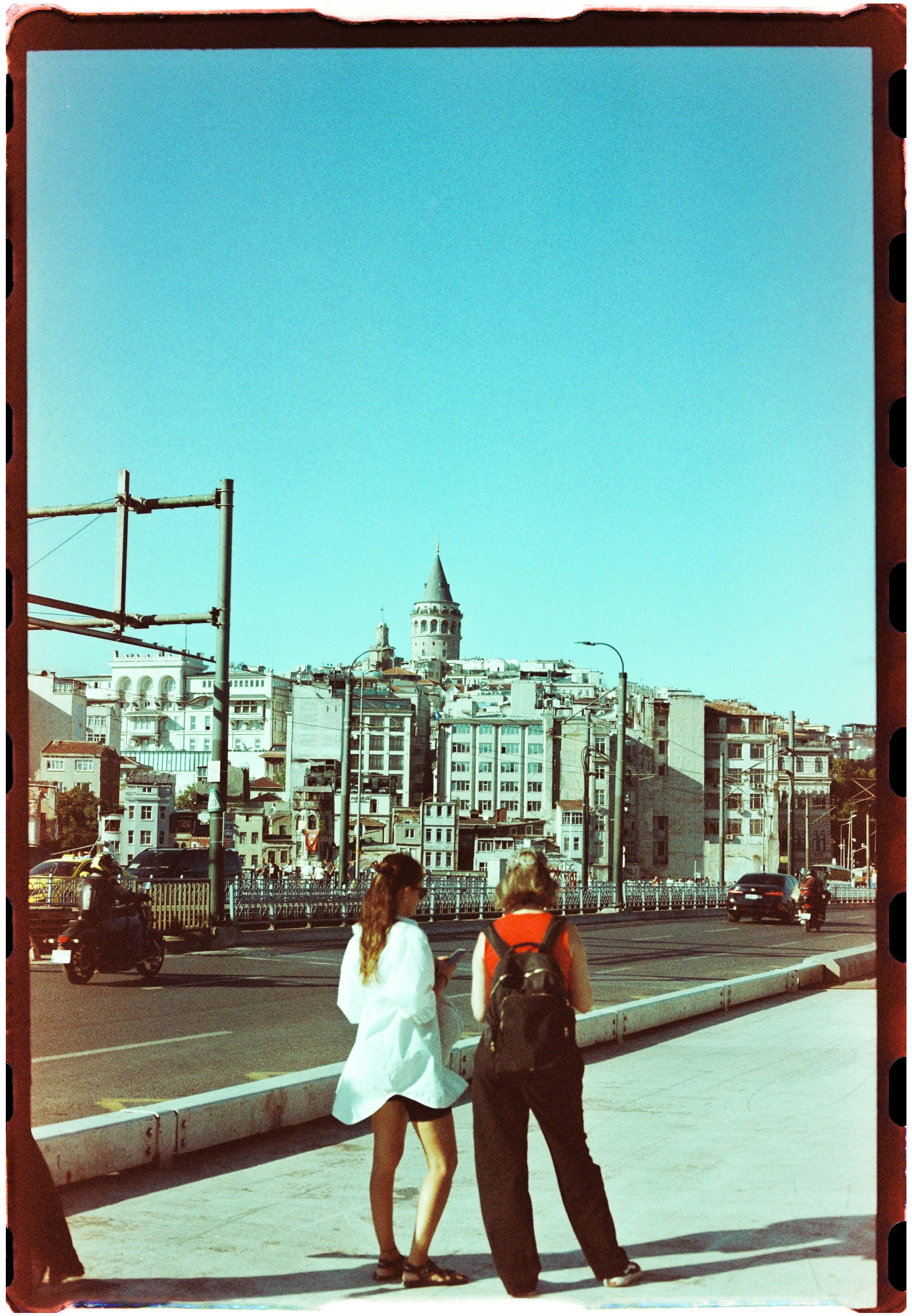 Two people on a bridge with the Galata Tower in Istanbul in the background