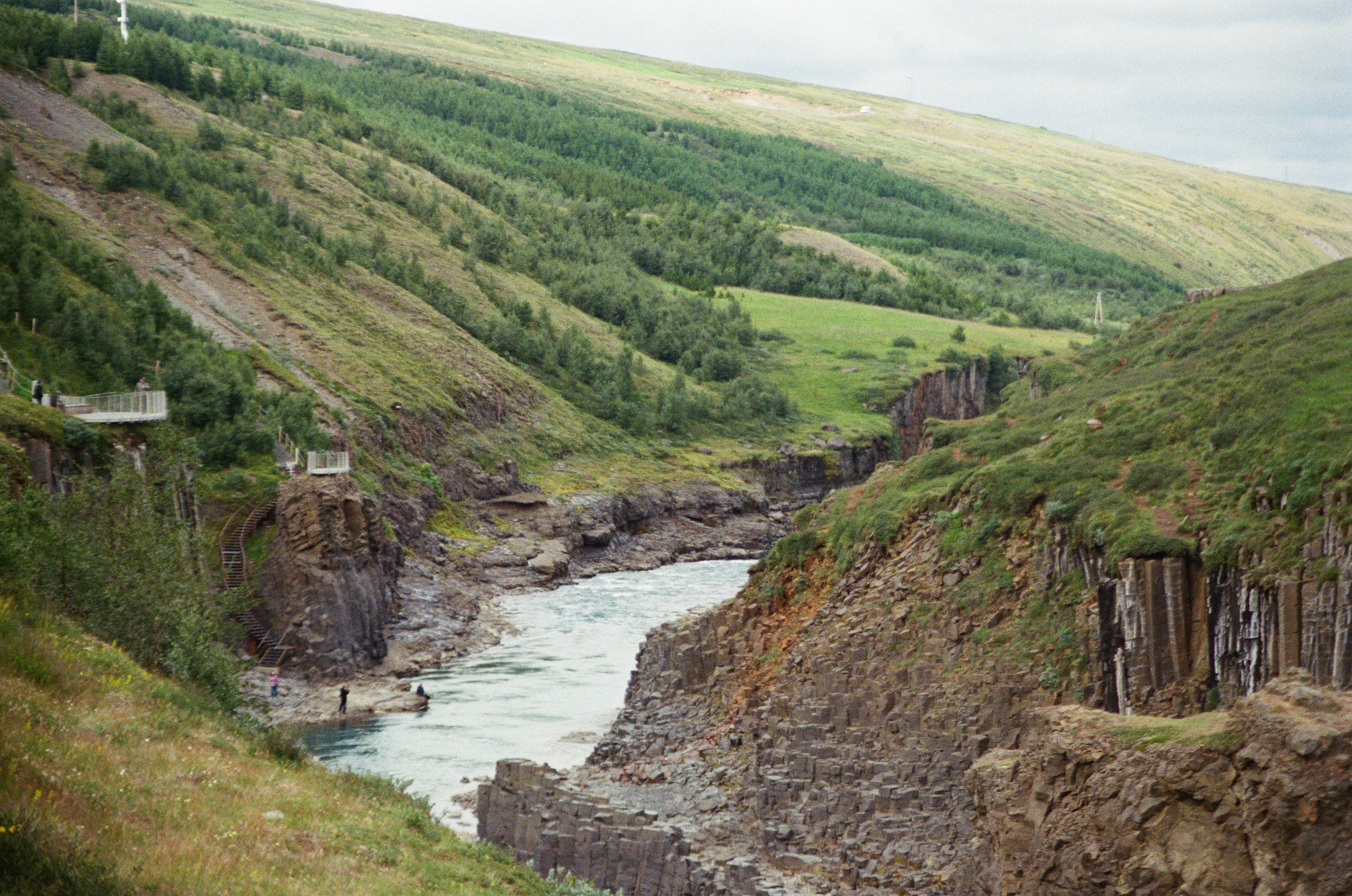 A river flowing through a deep basalt canyon with green hillsides