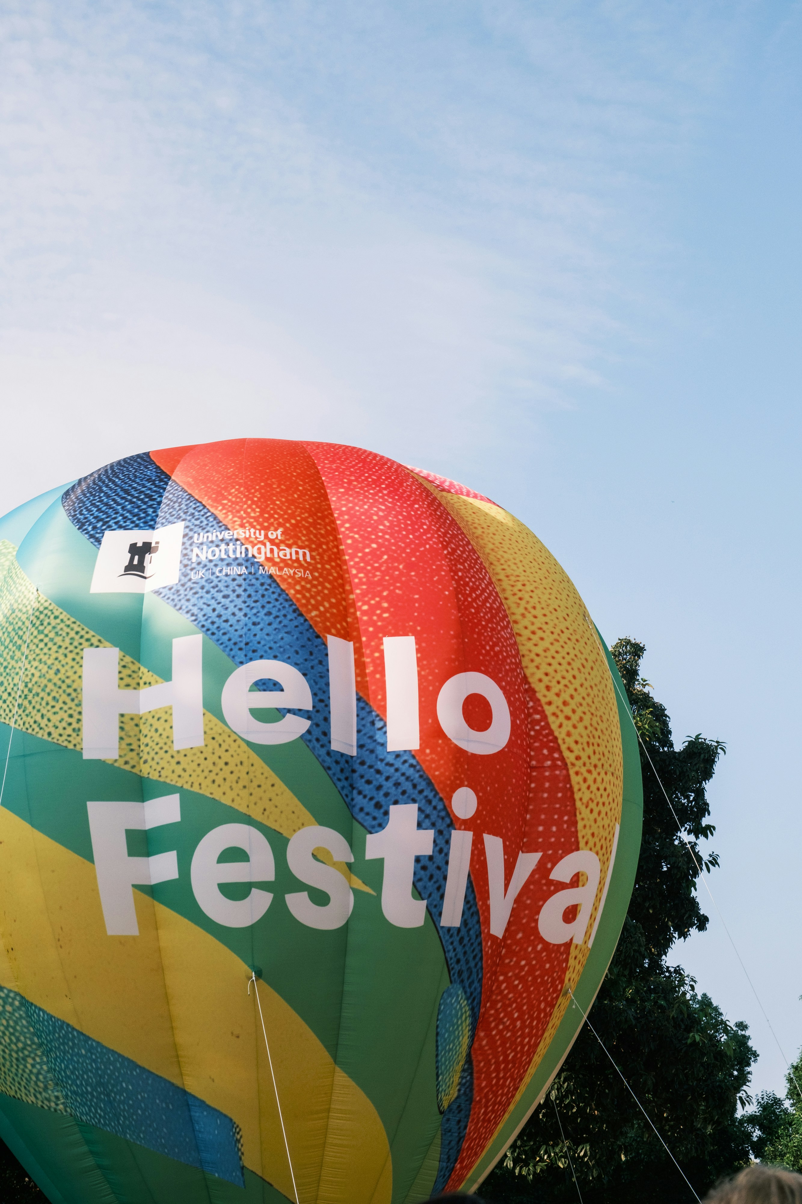 A colorful hot air balloon with the text Hello Festival against a blue sky
