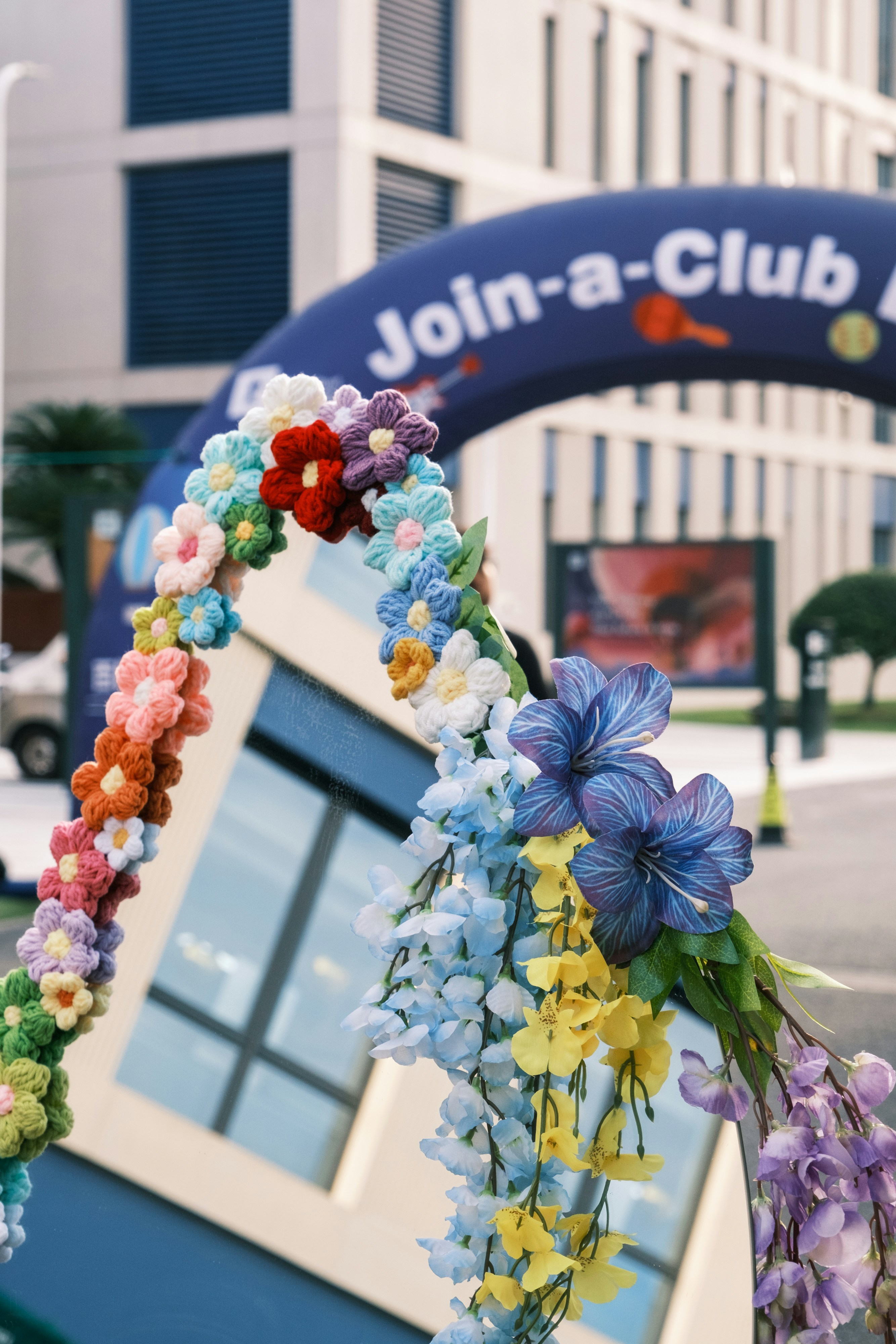 Crocheted flowers on an archway with artificial blue and yellow blossoms outdoors
