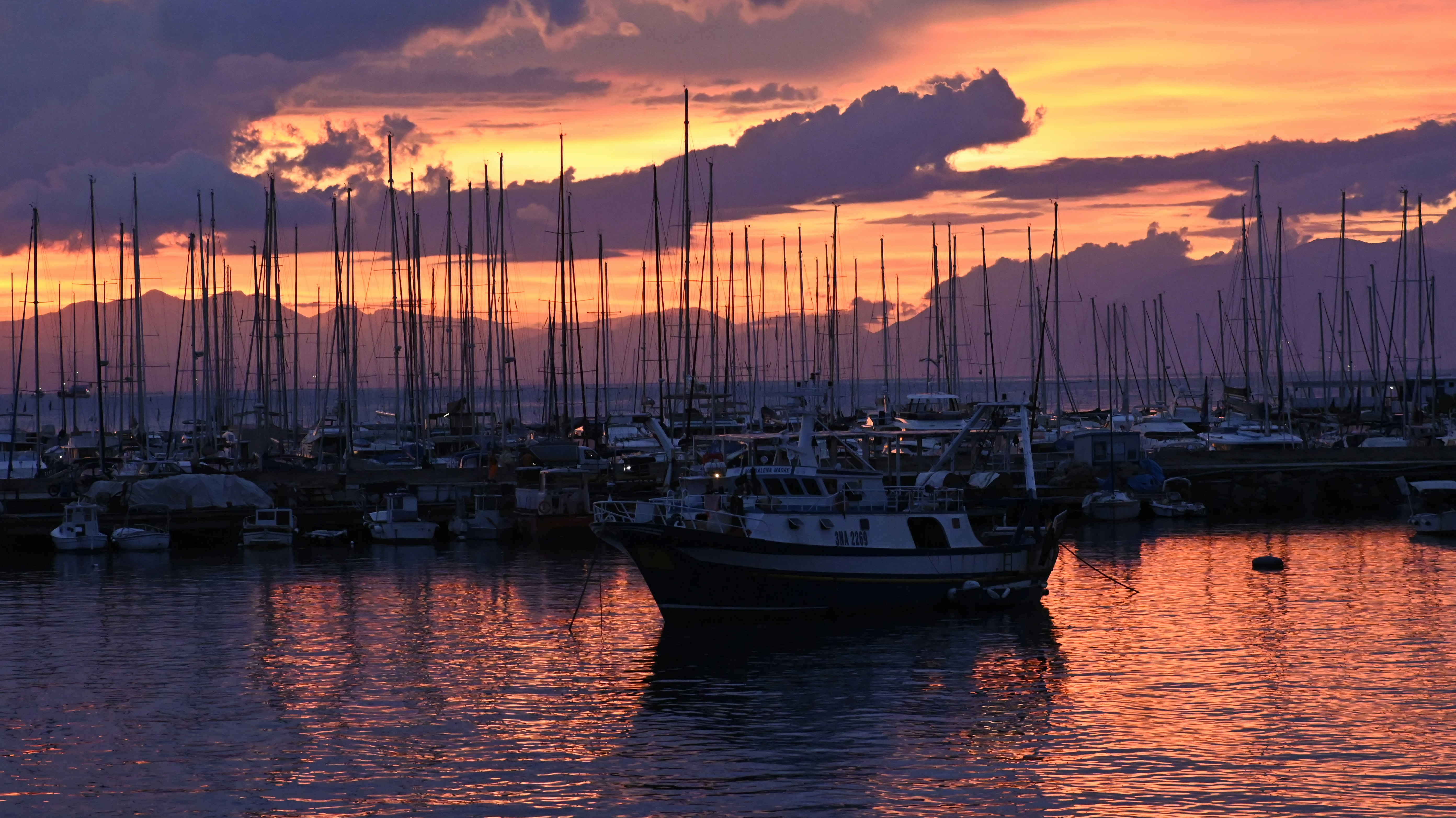 Boote lagen in einem Hafen unter einem leuchtend orangefarbenen und violetten Himmel