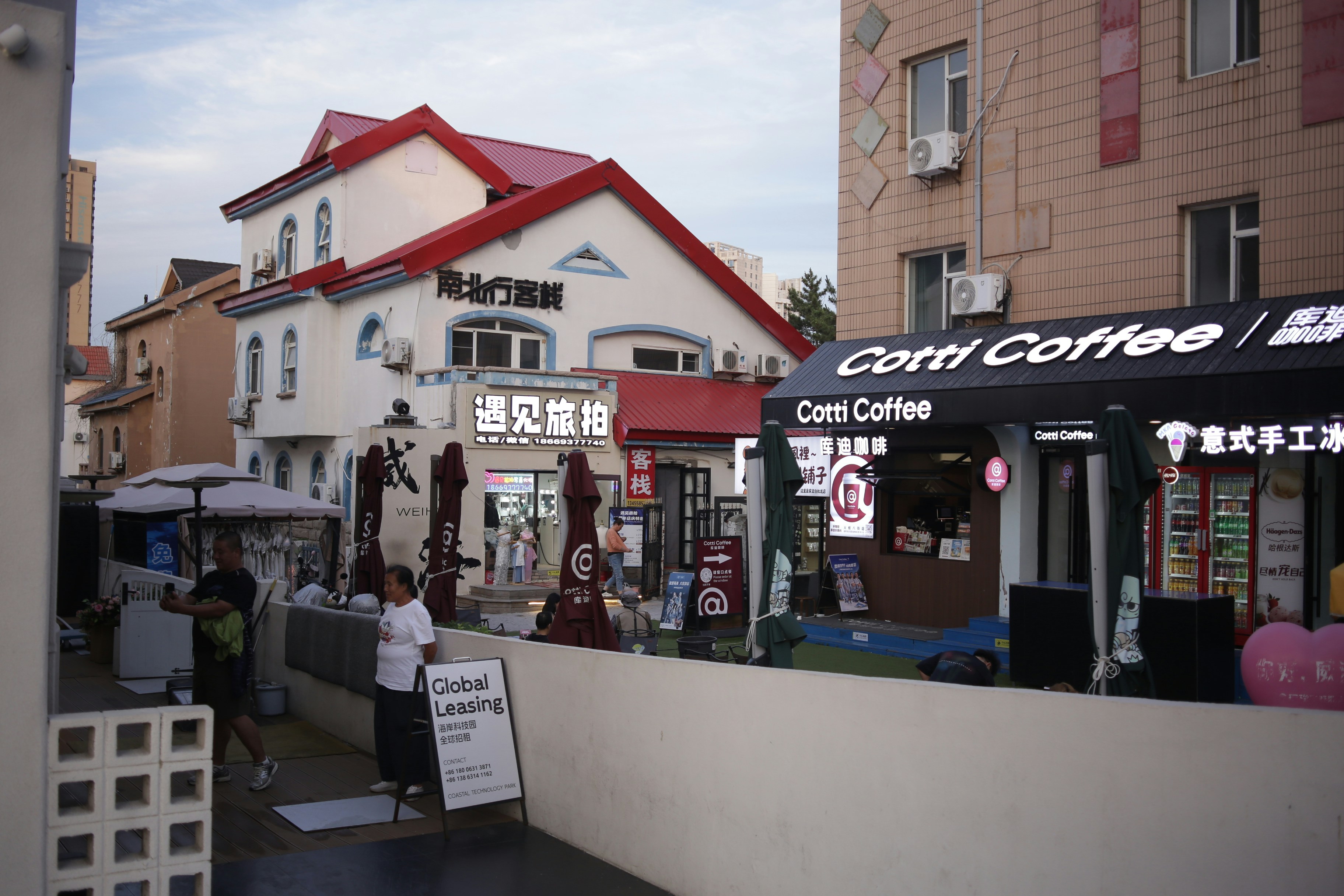 A Cotti Coffee storefront beside white buildings with red roofs in a courtyard