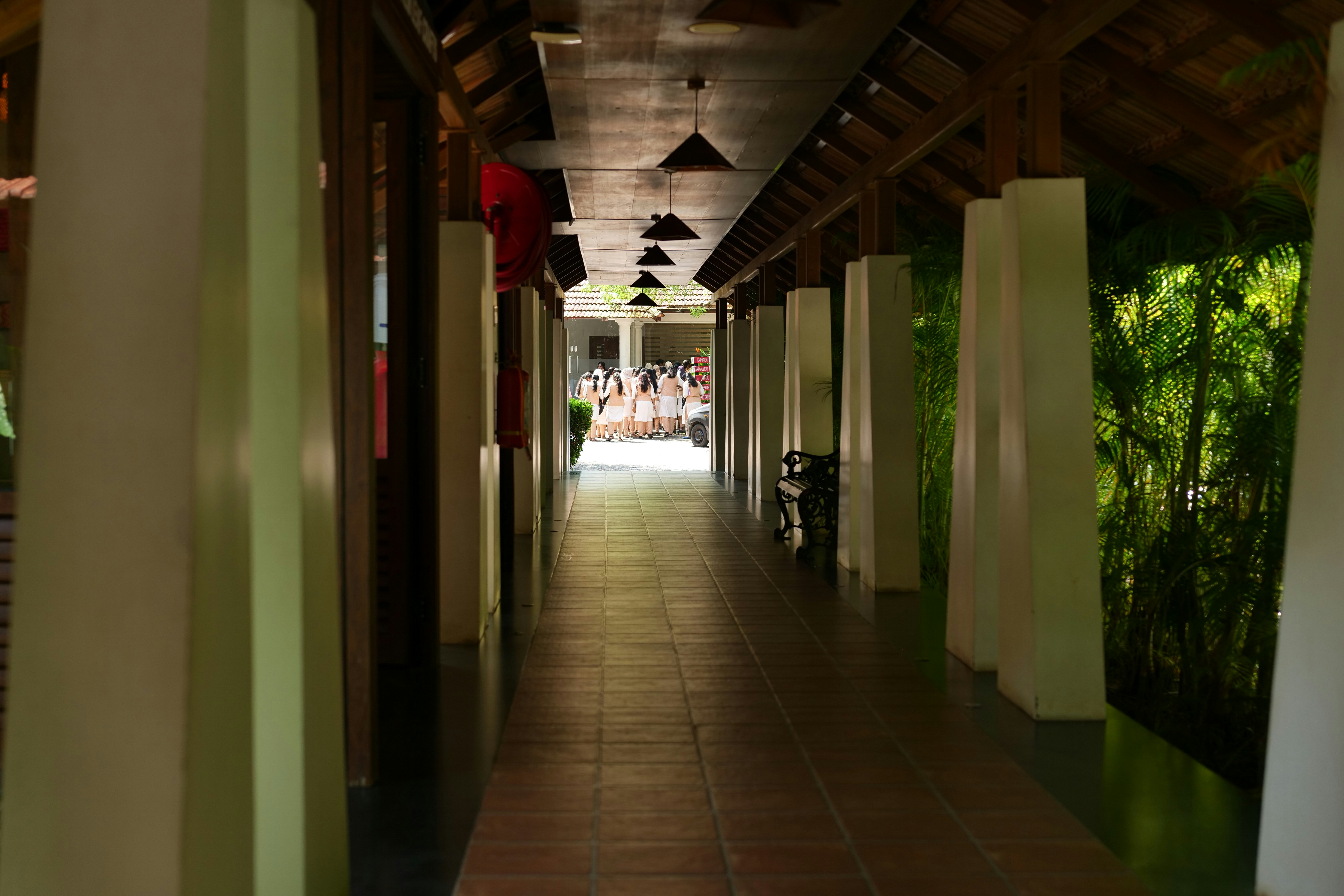 A group of people in white towels standing in a sunlit outdoor corridor