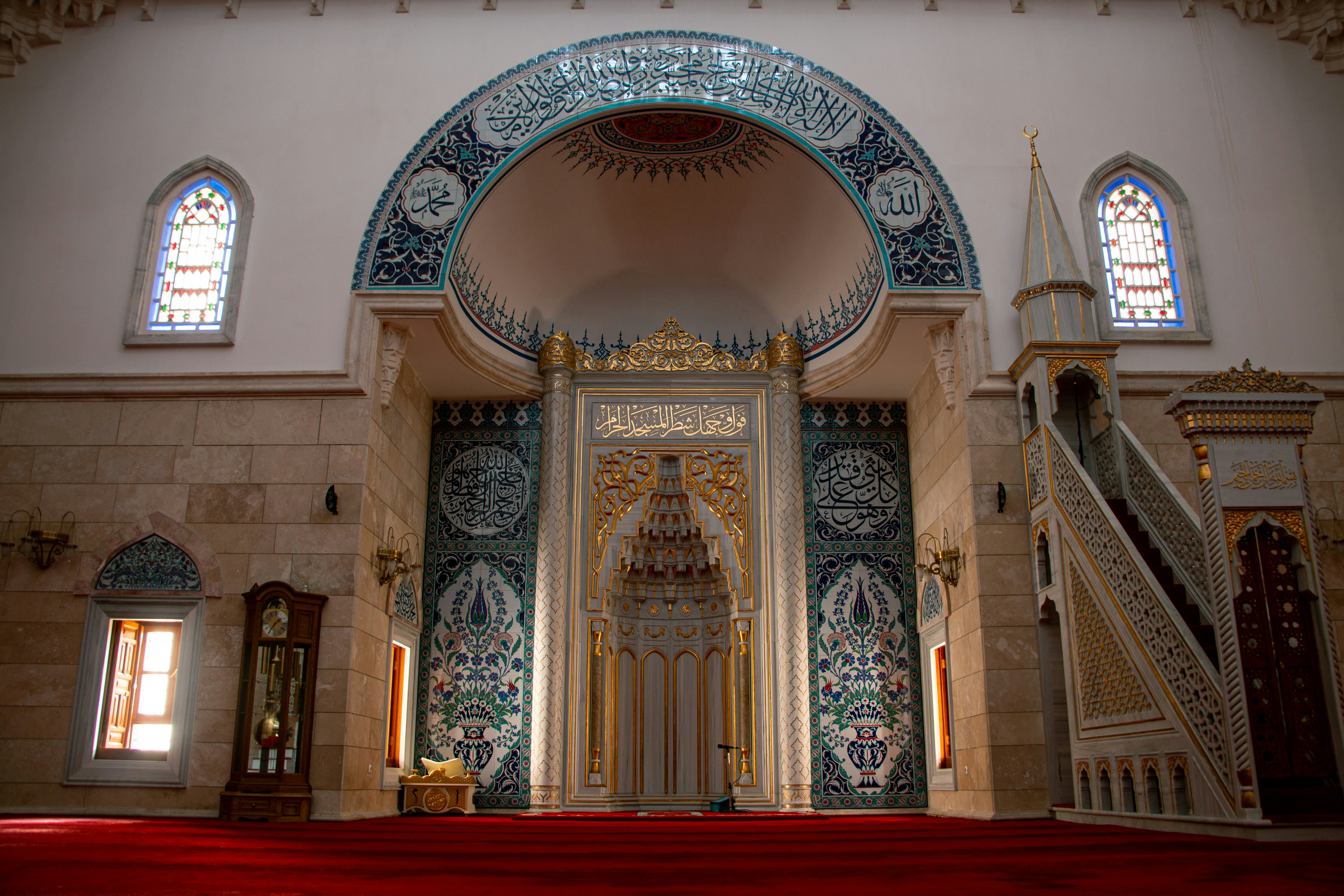 The mihrab and minbar inside a mosque with ornate tilework and Arabic calligraphy