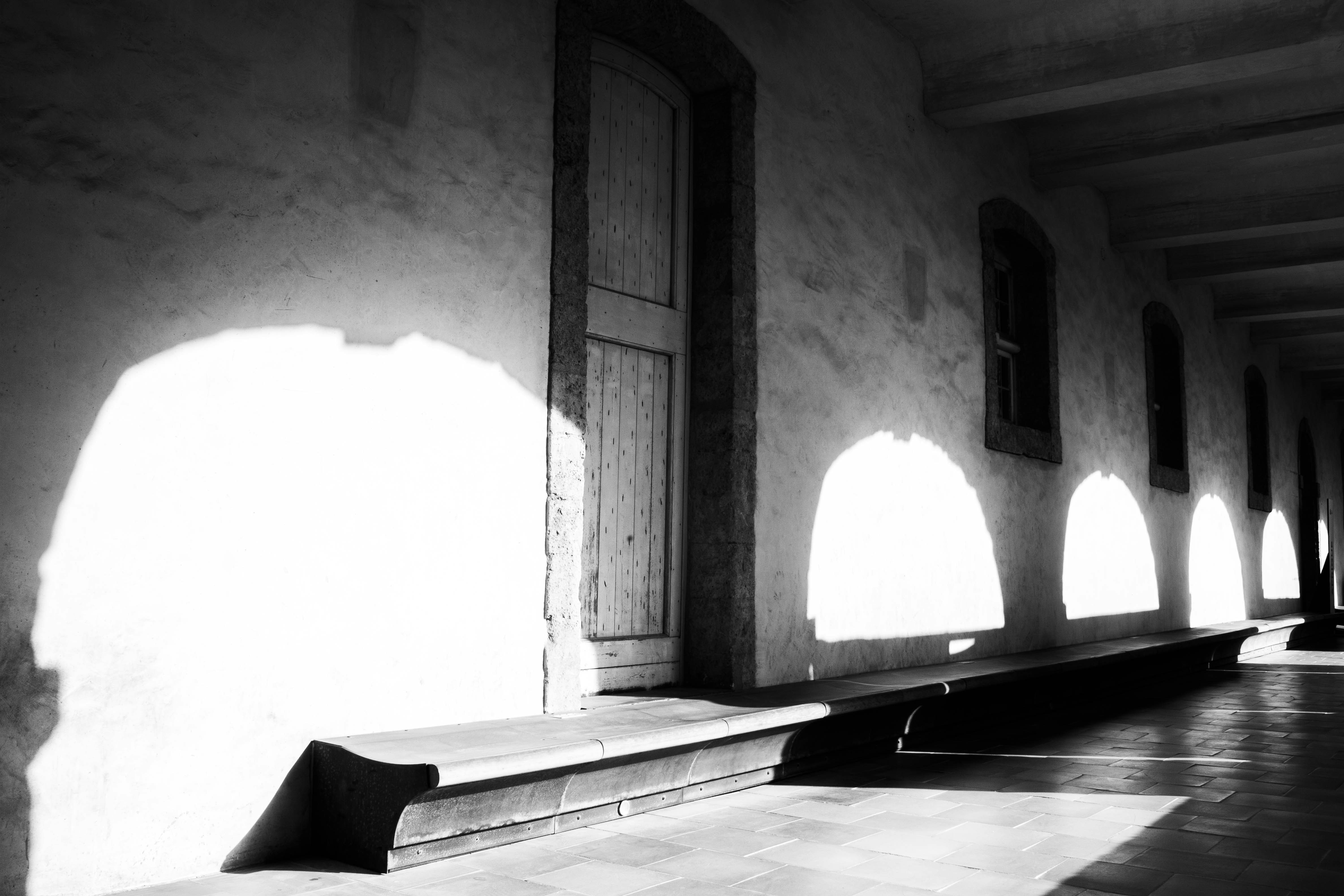 A long stone corridor with arched shadows cast on a textured wall