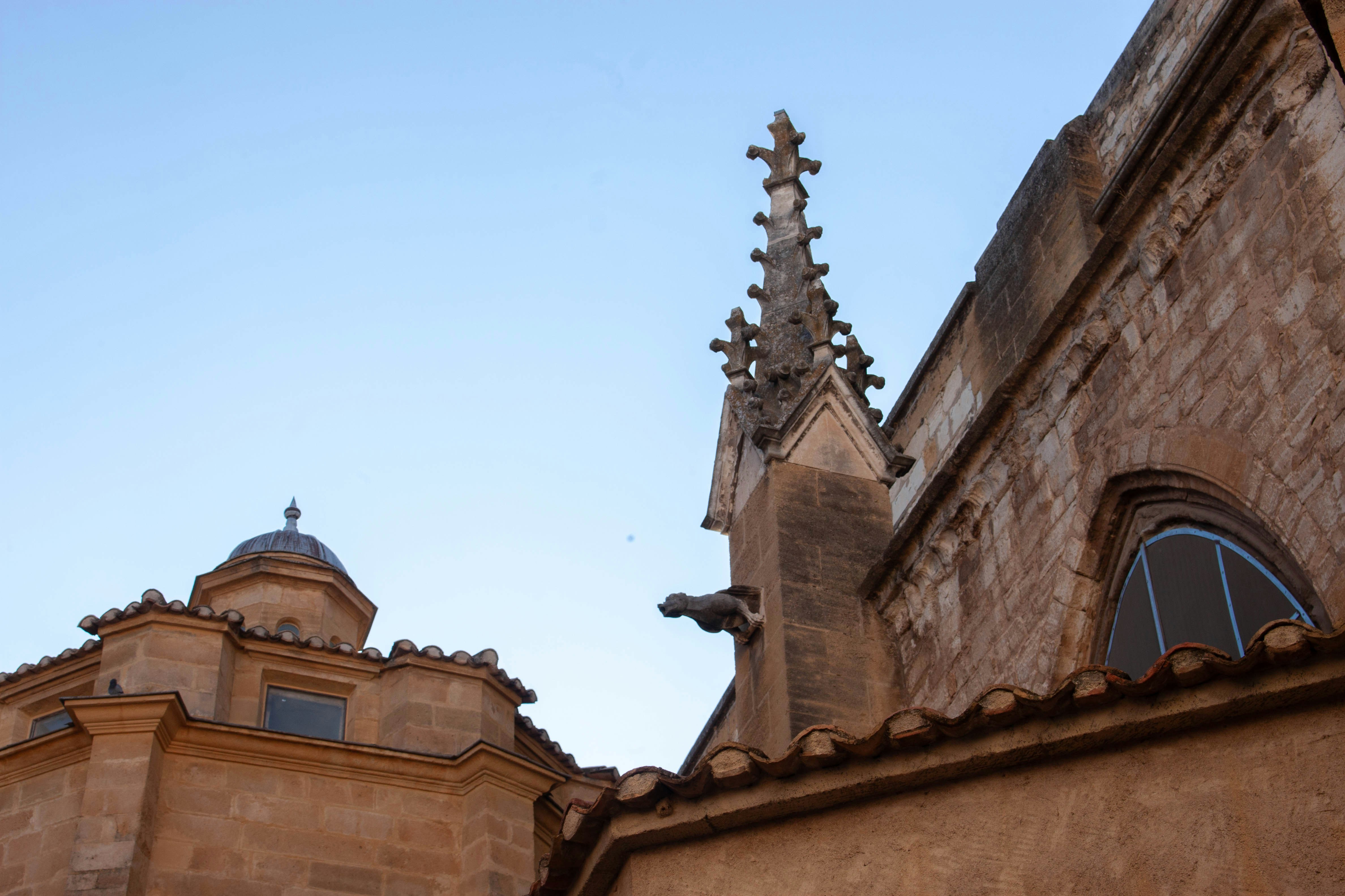 A stone gargoyle on a gothic church spire against a clear blue sky