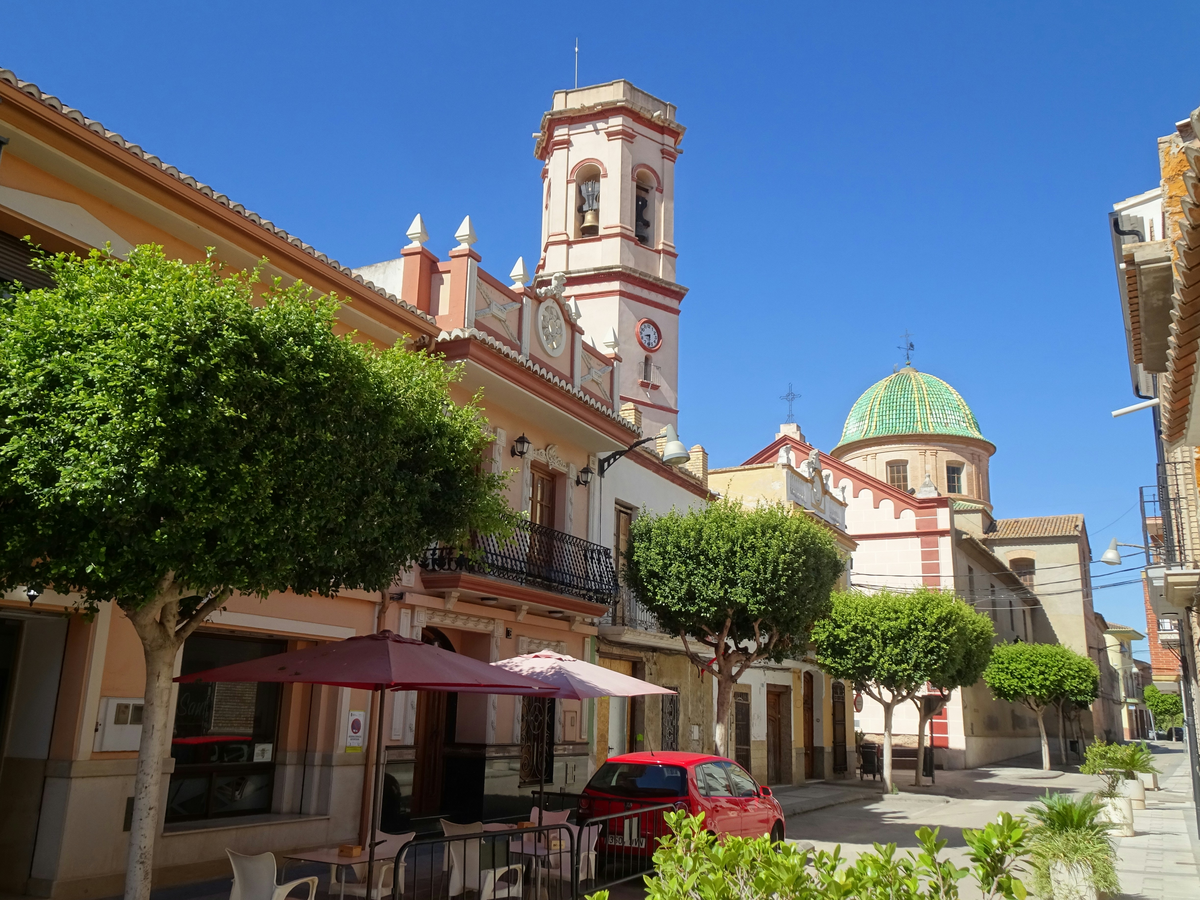 A street with a church tower and green dome under a clear blue sky