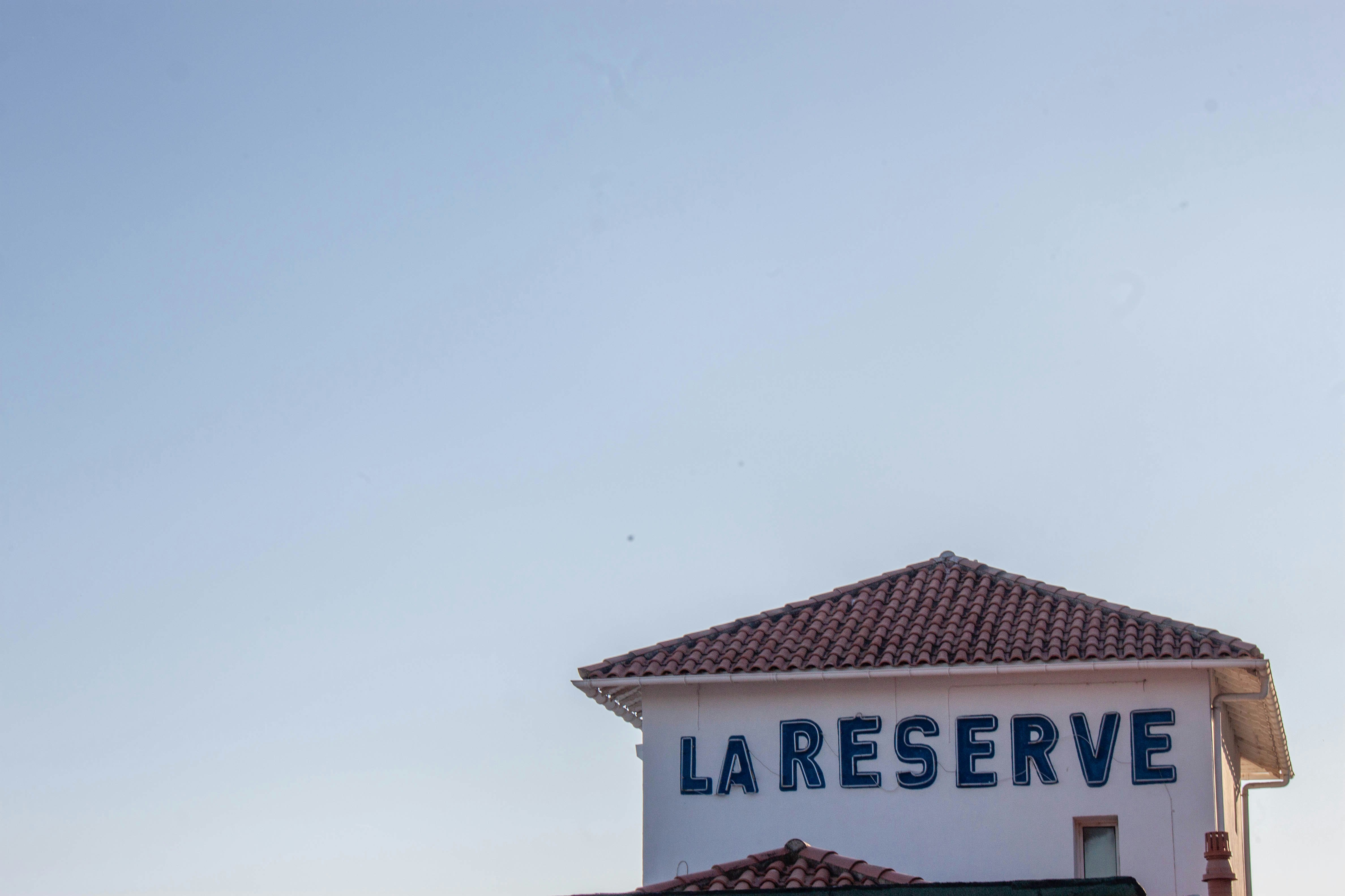 A white building with a tiled roof and a sign reading LA RESERVE