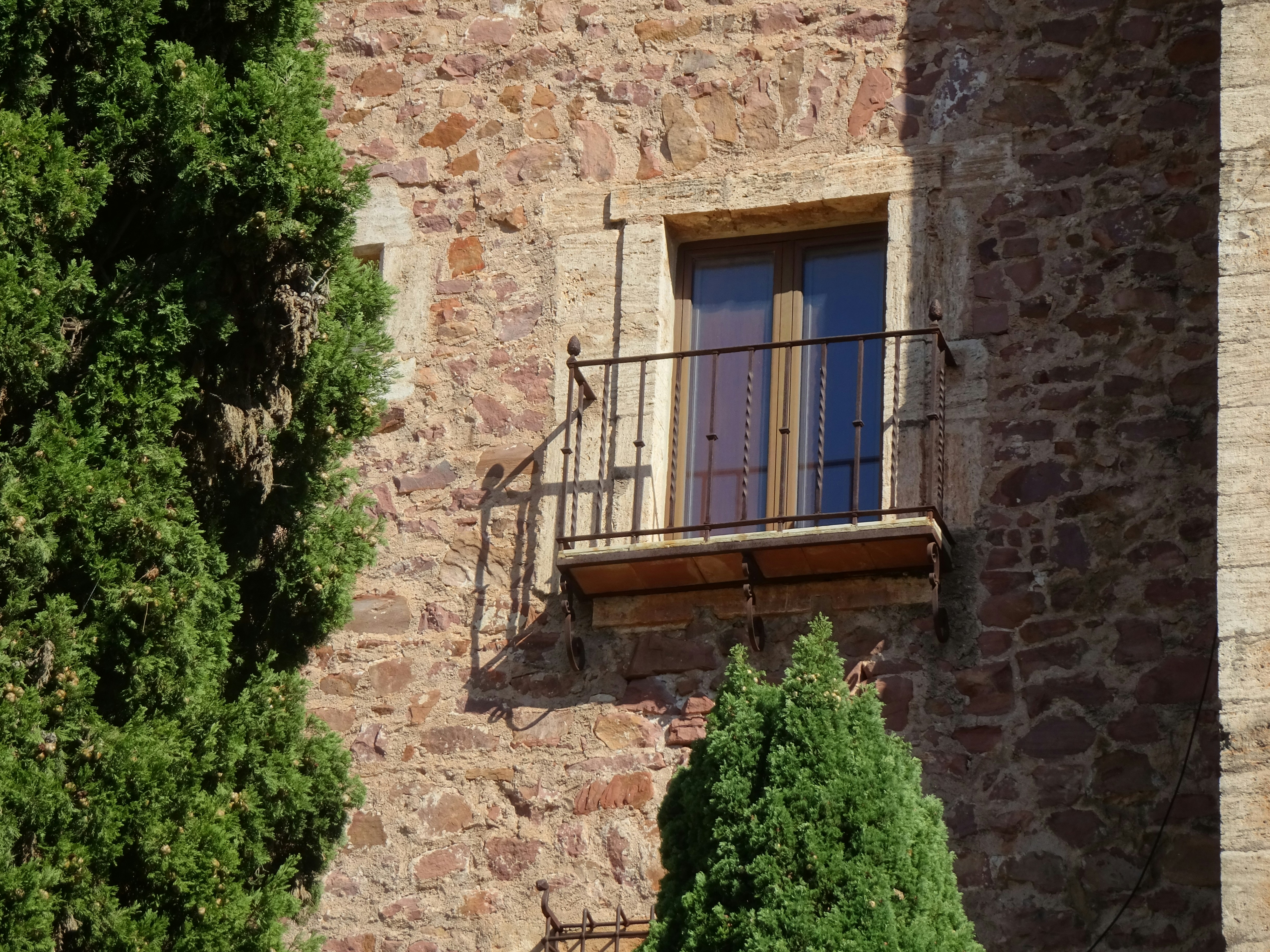 A small balcony with a metal railing on a rustic stone wall