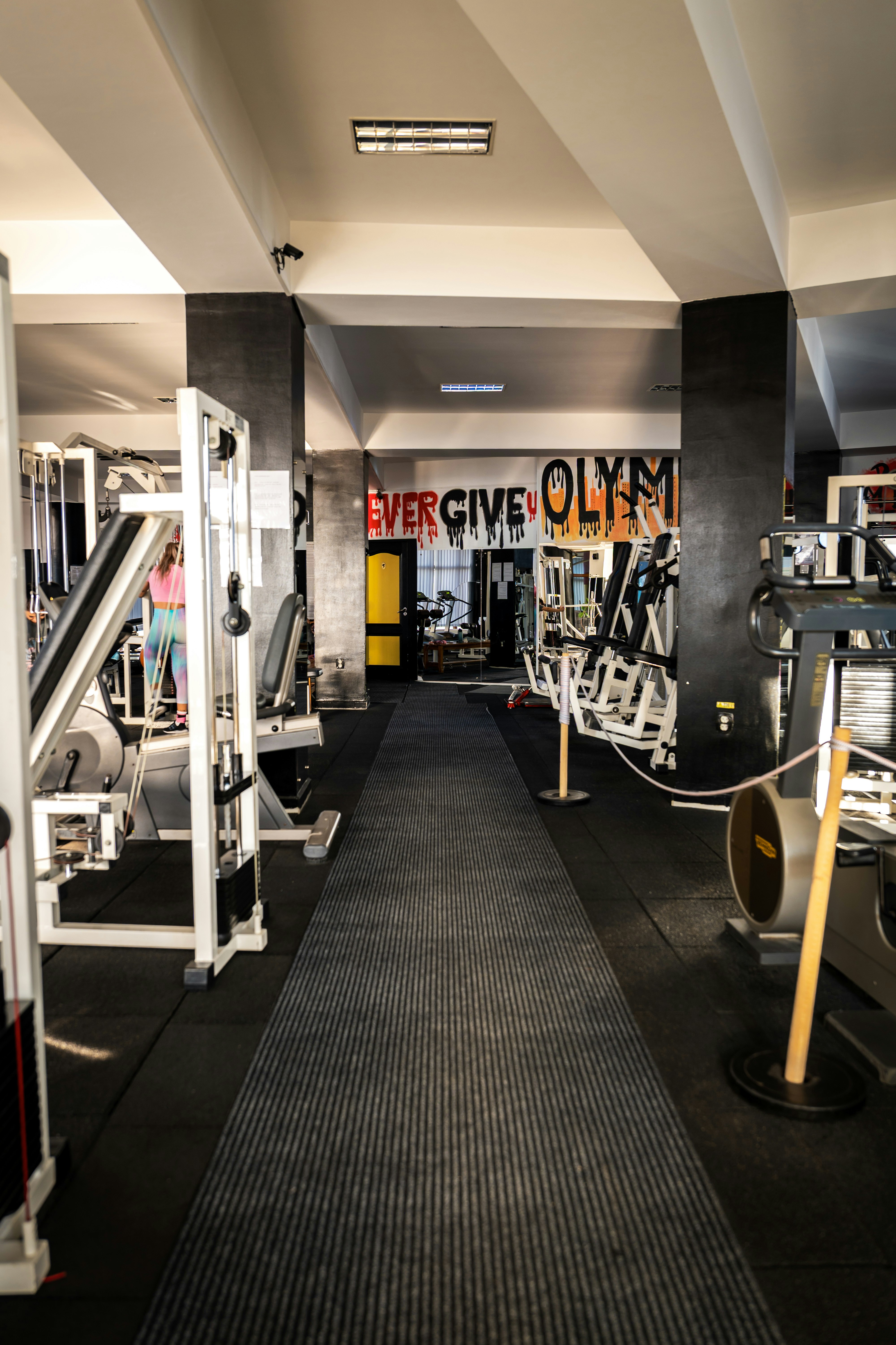 A gym interior with exercise machines and a long runner rug on the floor