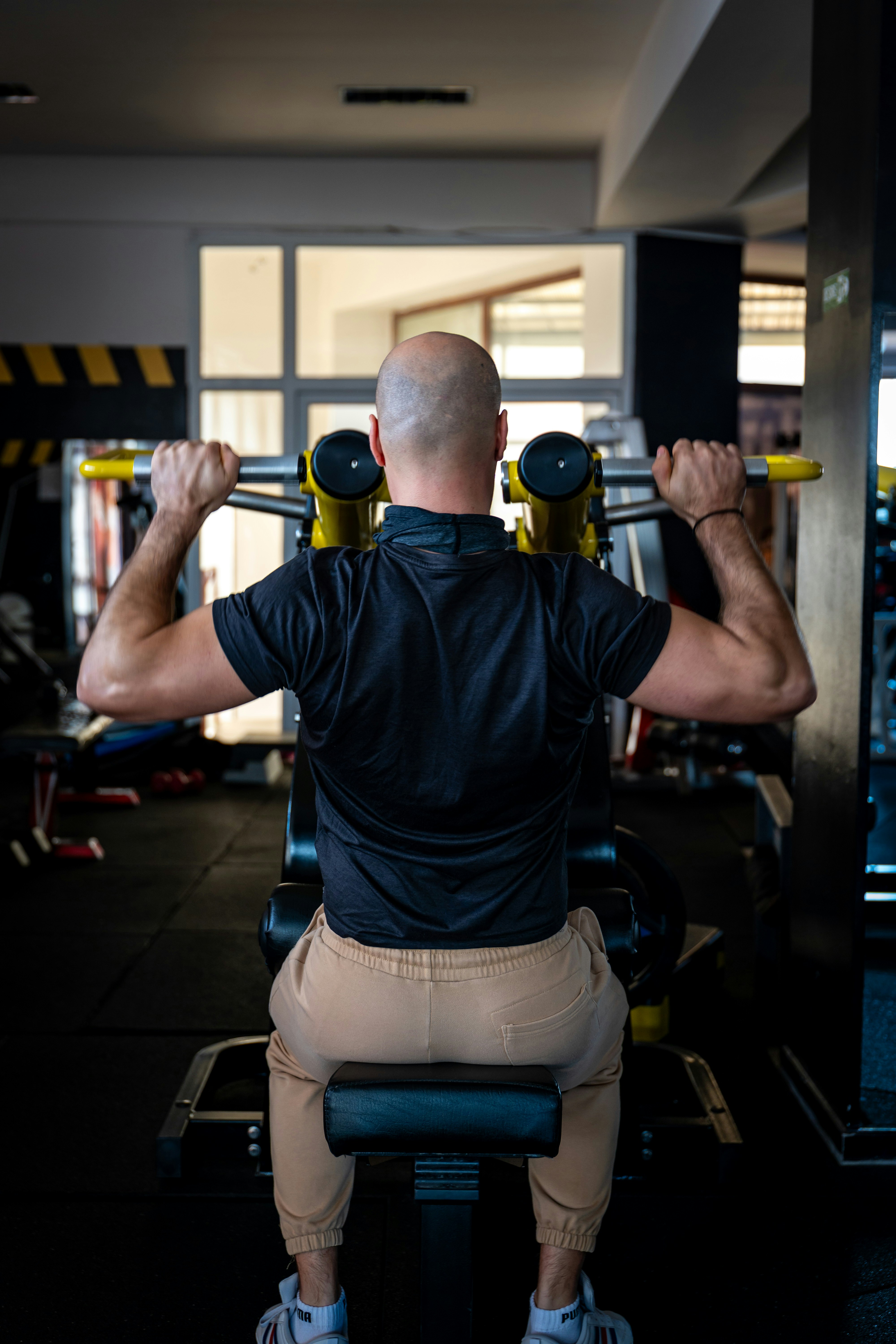 Hombre entrenando en una máquina de press de hombros en el gimnasio