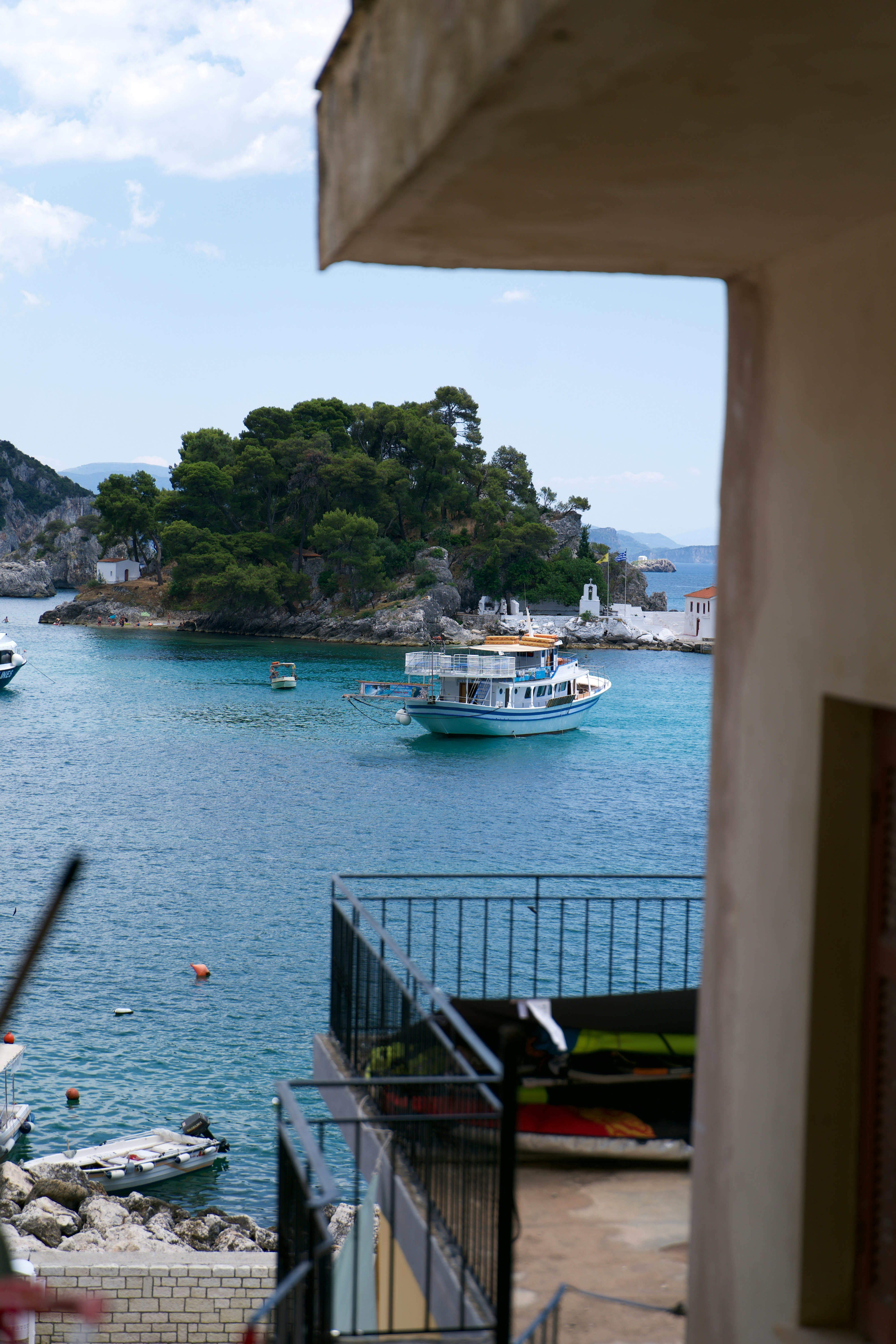 A boat anchored in a blue bay near a small island with trees