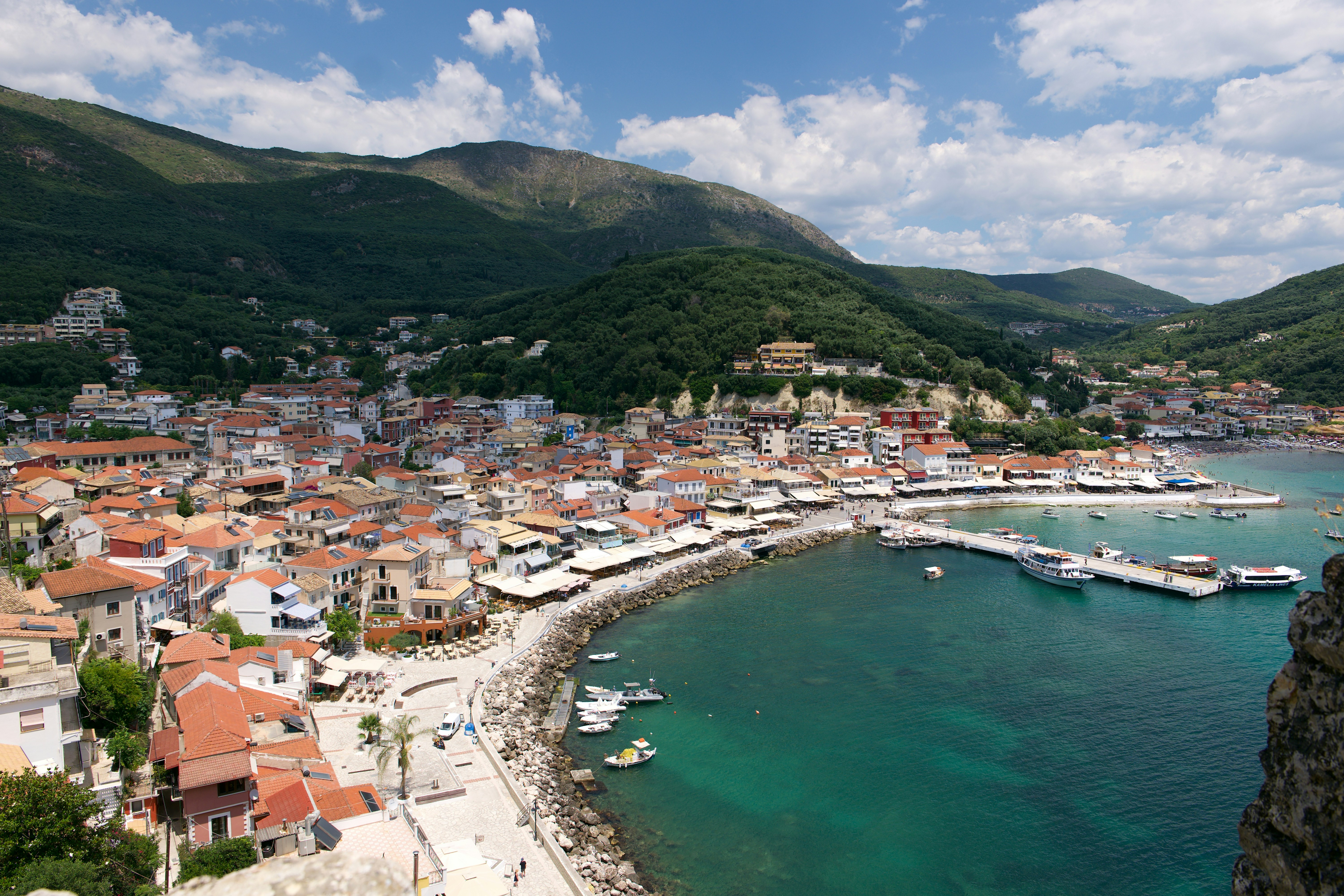 Una città costiera con edifici dal tetto rosso lungo una baia turchese a Parga, Grecia